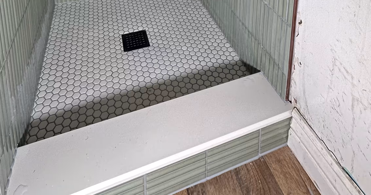 Finished green fluted tile shower with a tiled curb opening onto wood flooring in an Arvada, CO bathroom
