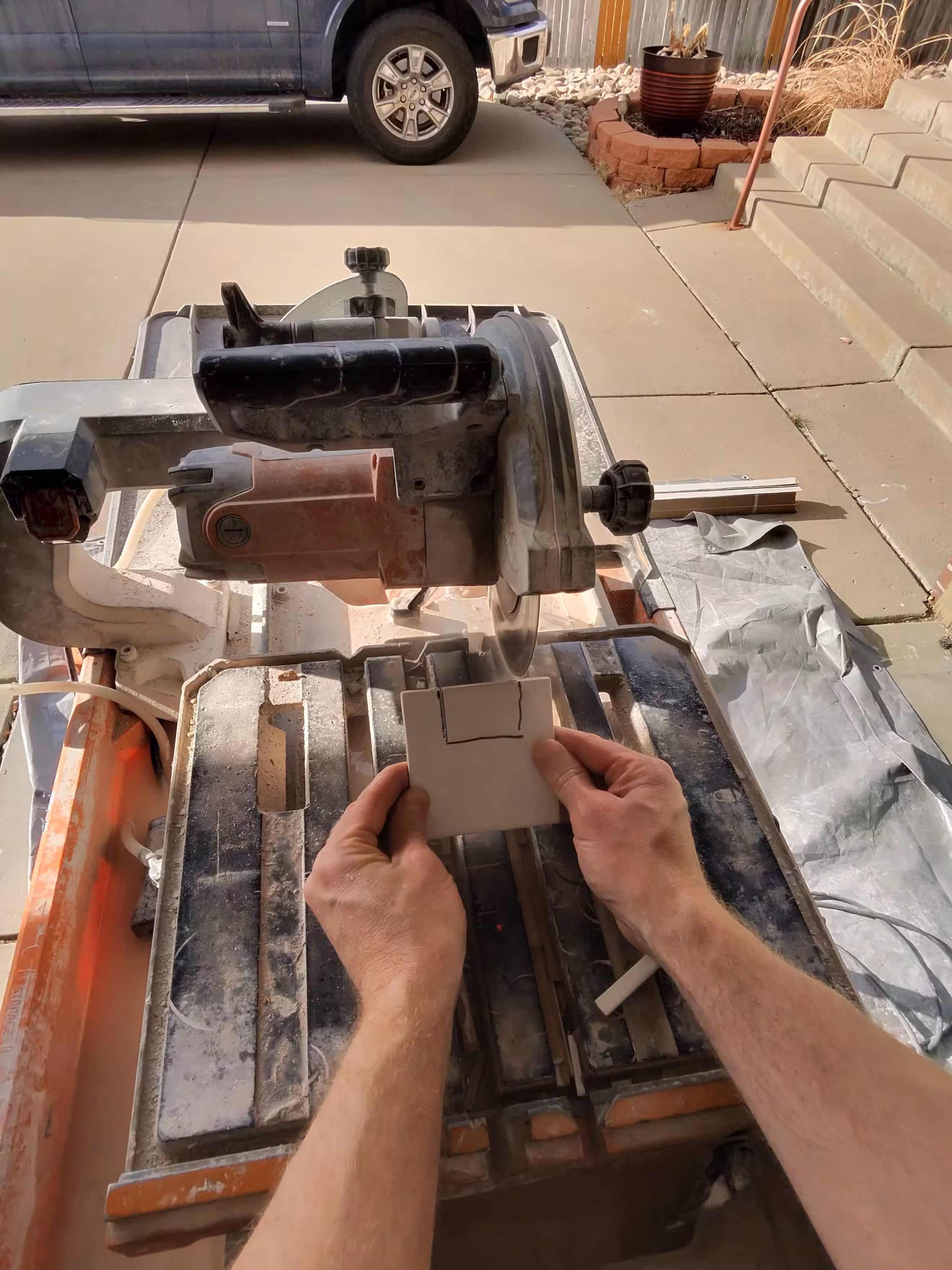 Cutting a notch into a glossy white square tile on a wet saw to fit around an outlet for this Aurora backsplash