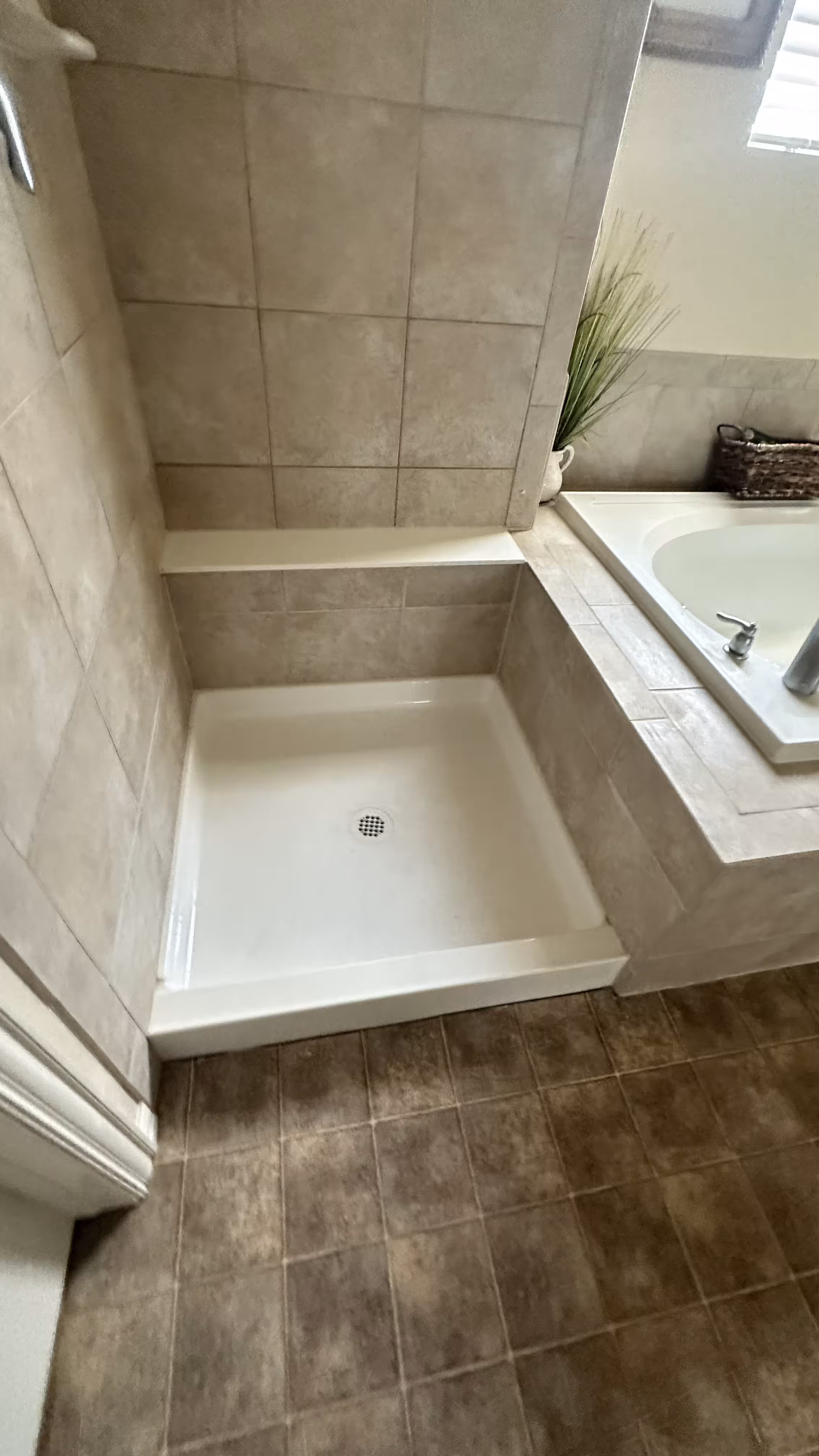 Close-up of the new white shower base and tiled bench corner after the Aurora leak repair rebuild