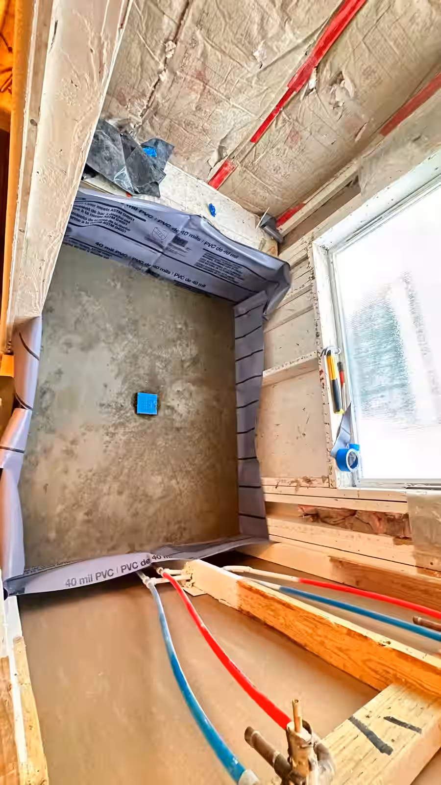 Completed PVC shower pan liner installation with integrated plumbing penetrations