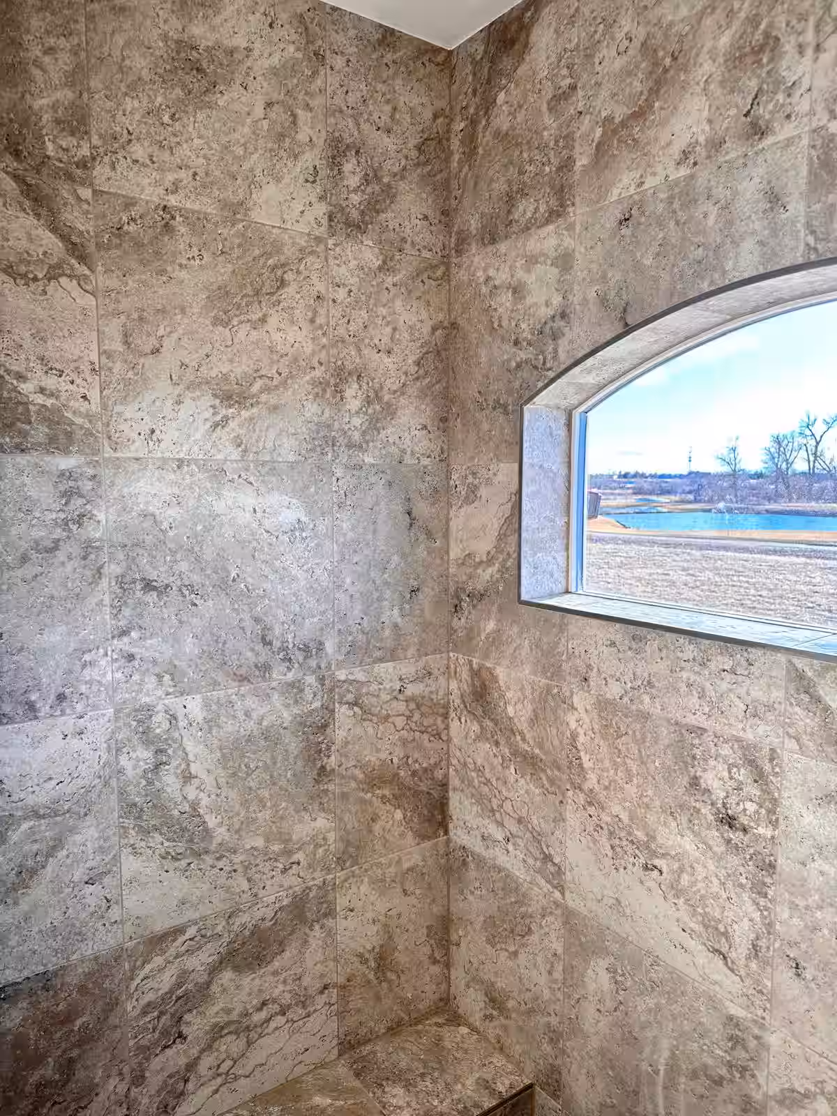 Bathroom shower tile installation completed with natural stone walls