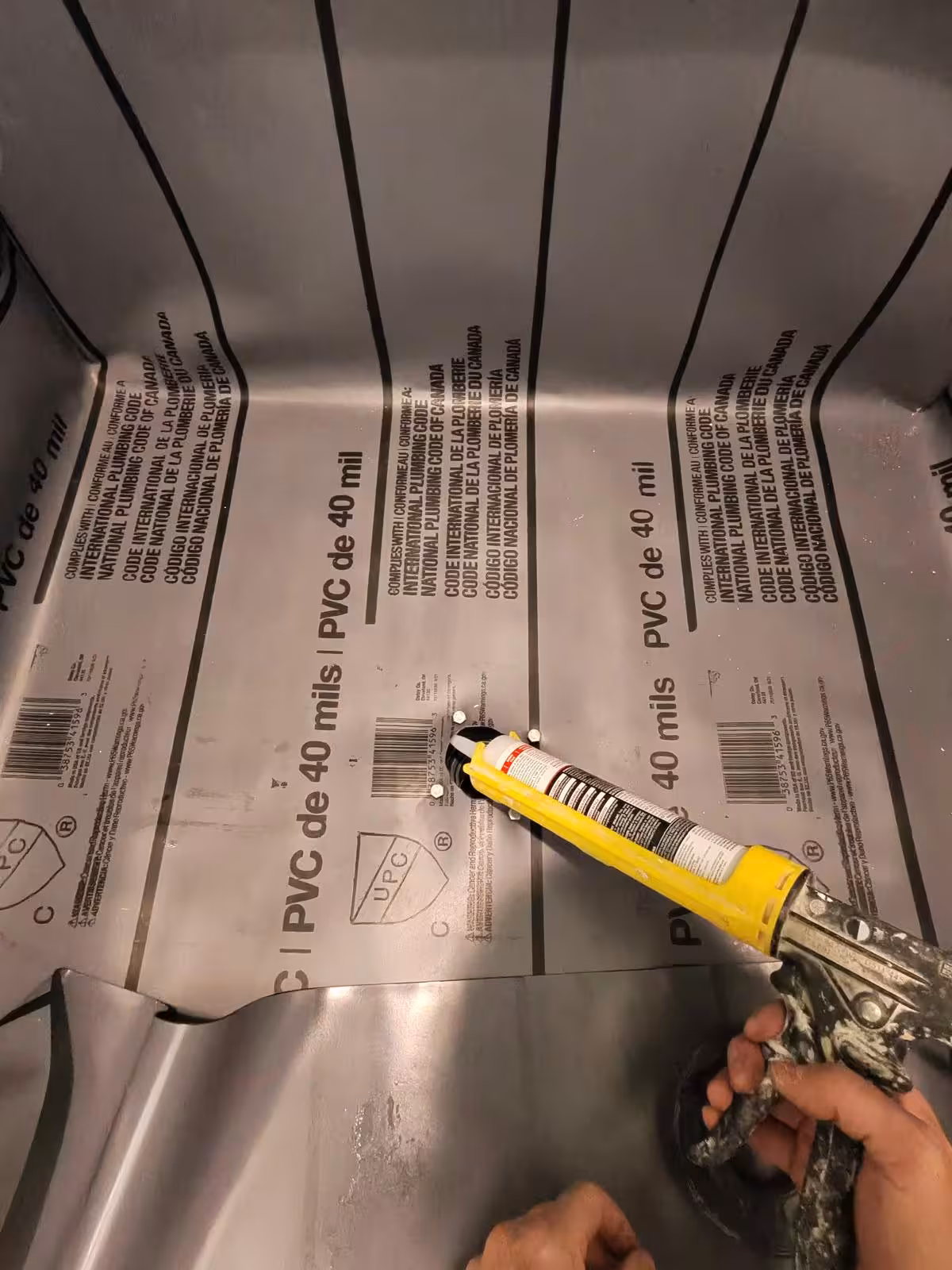Applying 100% silicone sealant to PVC shower liner drain connection Denver