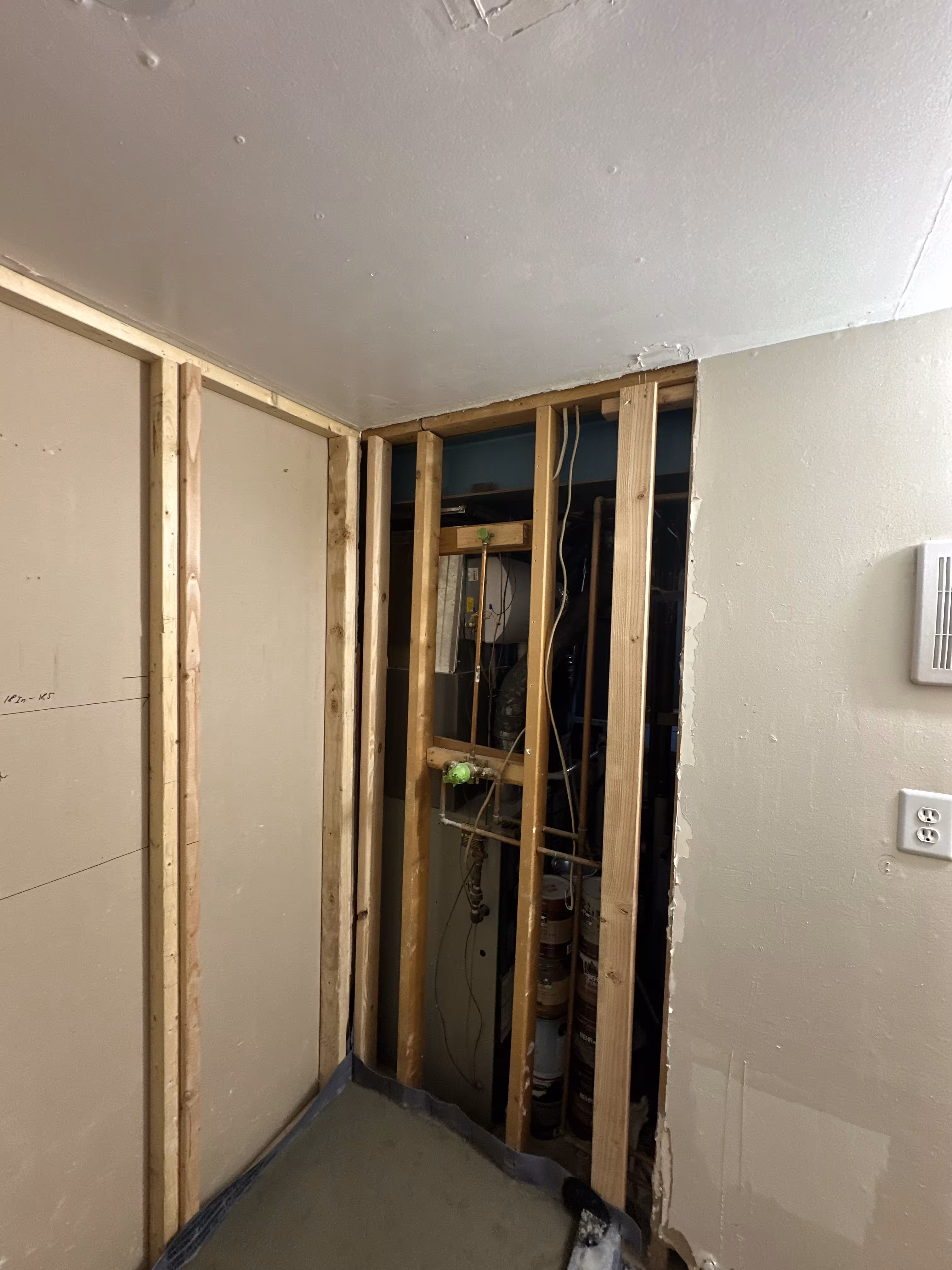 Open stud framing with plumbing access before the green stacked tile shower remodel in Commerce City, CO