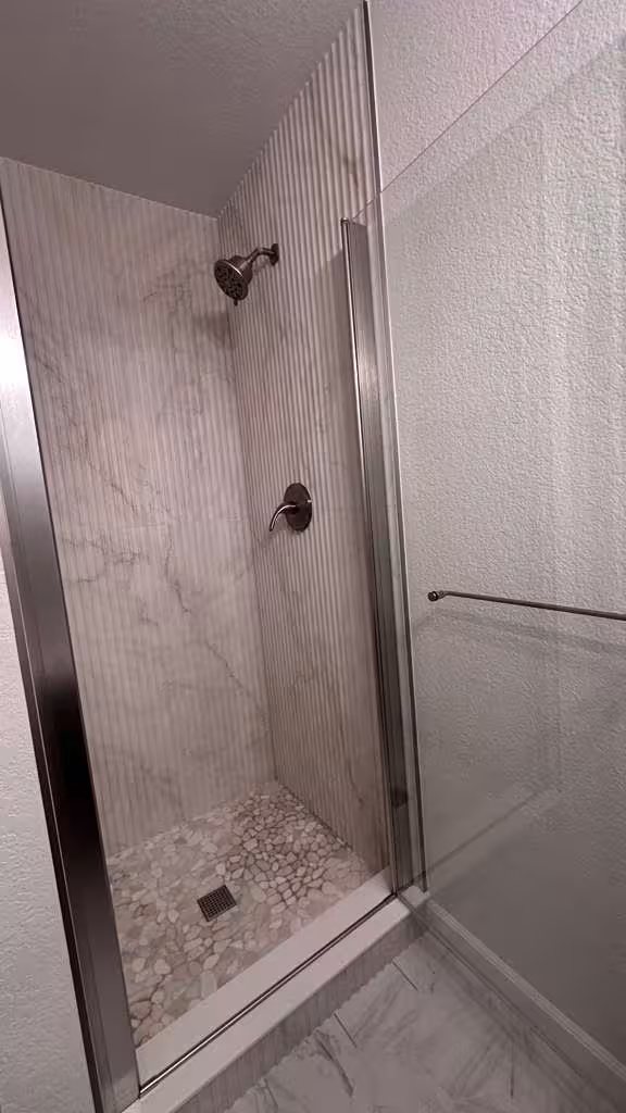 Final shower remodel with vertical tile installation and pebble floor detail
