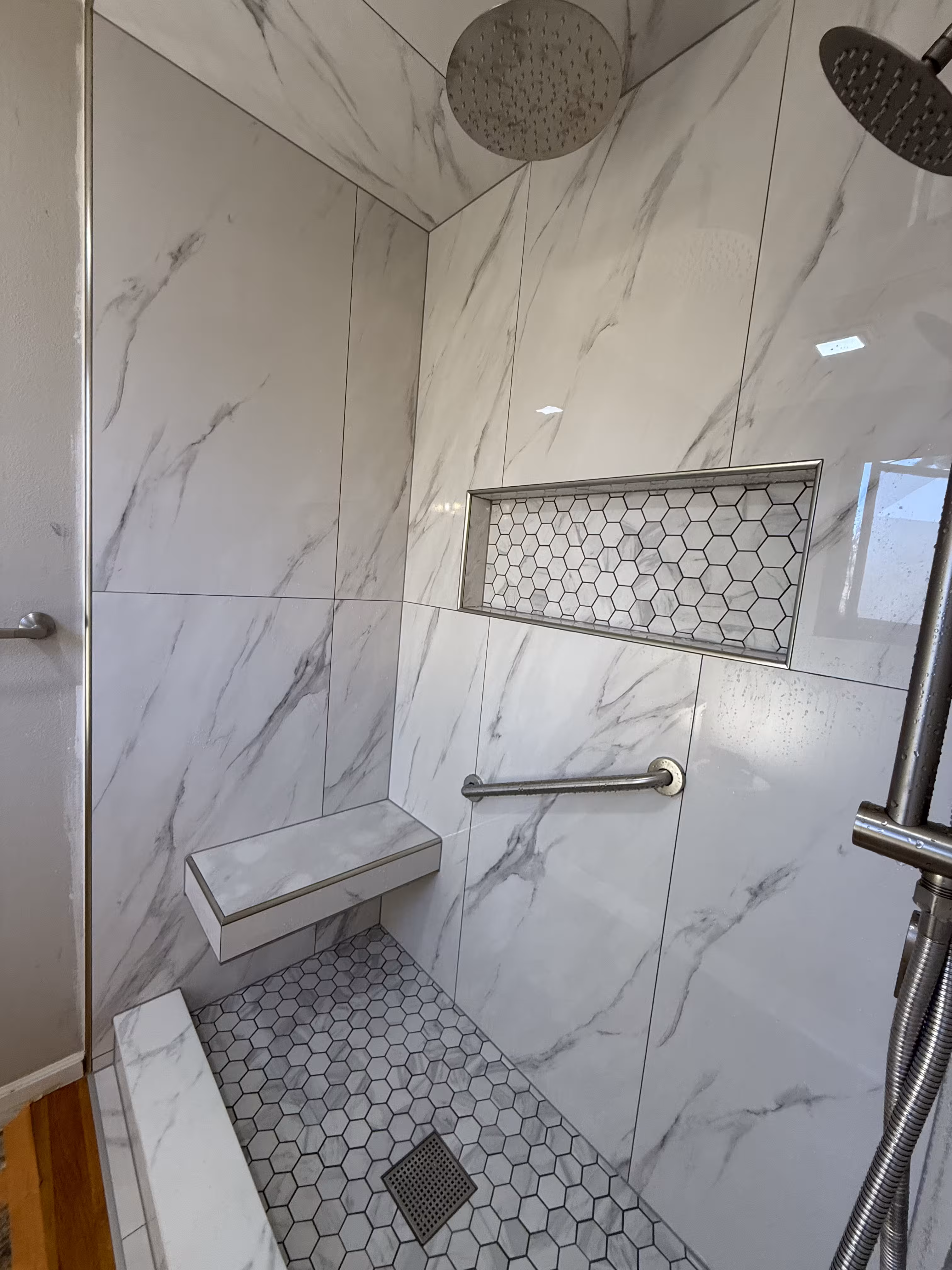 Finished marble-look shower remodel in Highlands Ranch with floating bench and large-format tile