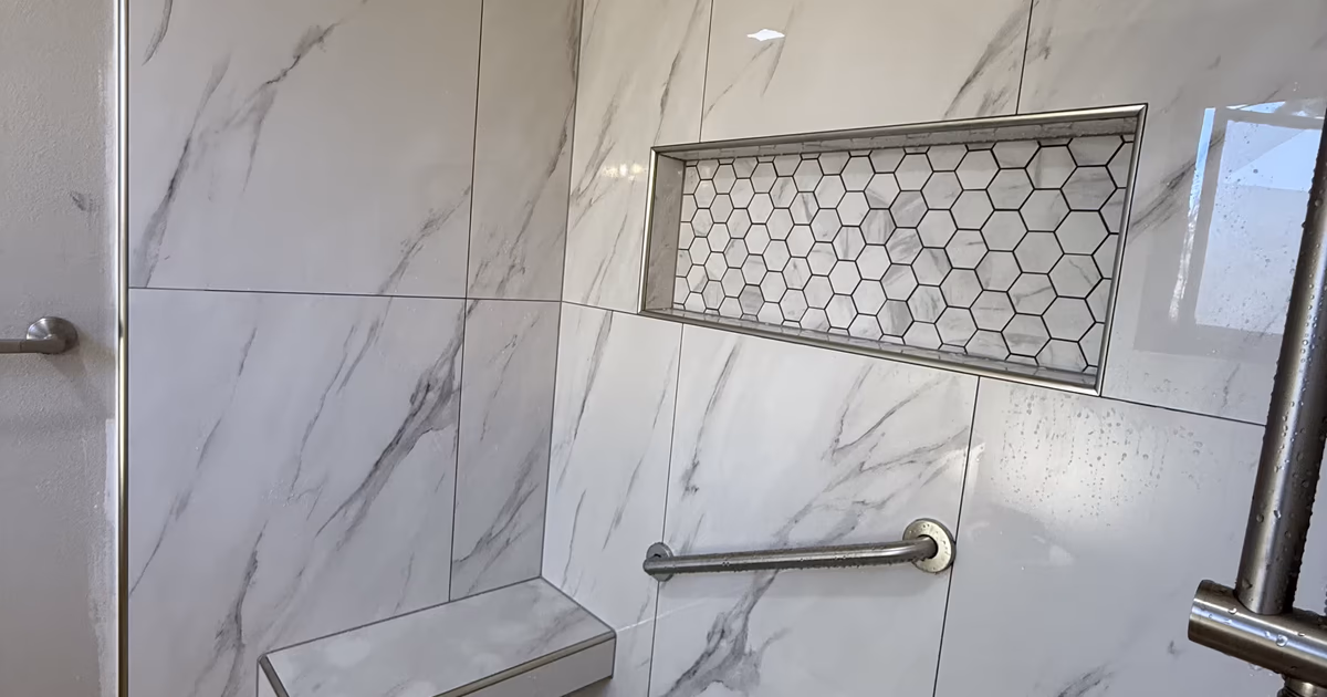 Grab bar above a floating bench and a hexagon-mosaic niche in a finished marble-look tile shower in Highlands Ranch, CO