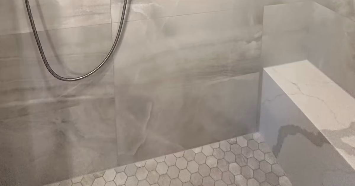 Finished steam shower corner with a mitered marble-look tile edge on the bench, large-format porcelain walls and a hexagon mosaic floor in Denver, CO