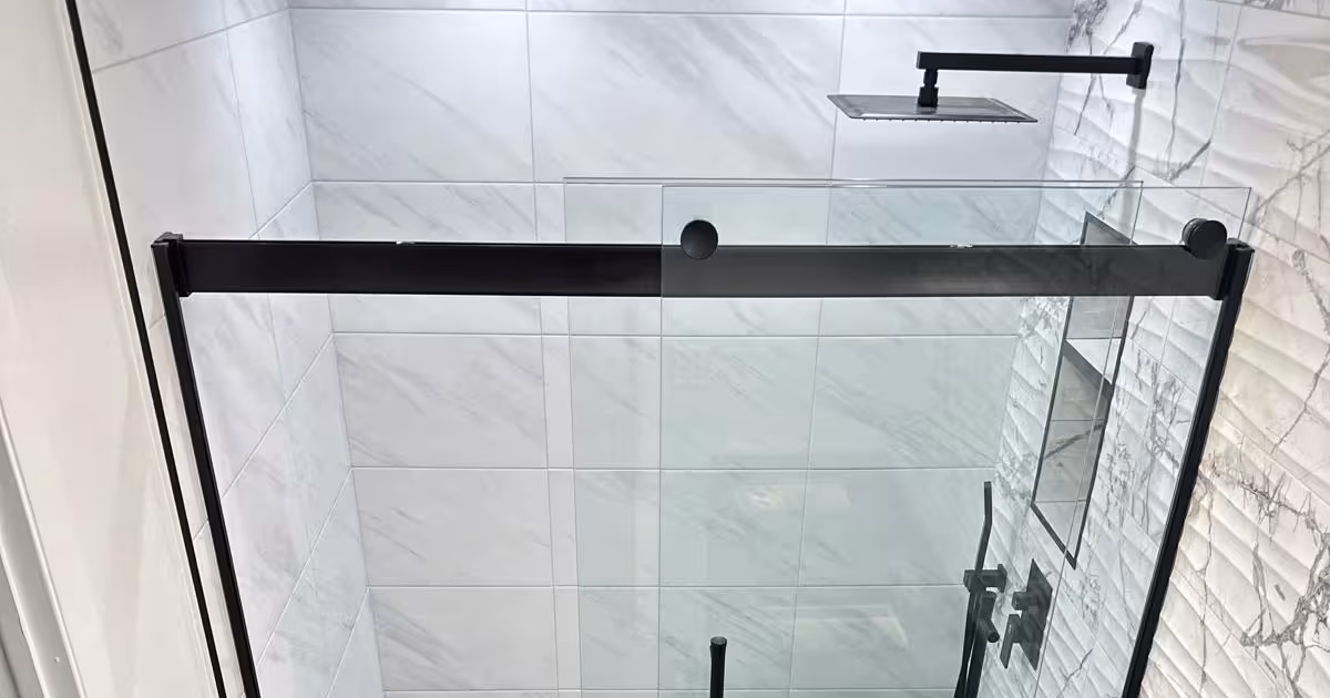 Finished walk-in tile shower with a black-framed glass door and dark mosaic floor in Aurora, Colorado