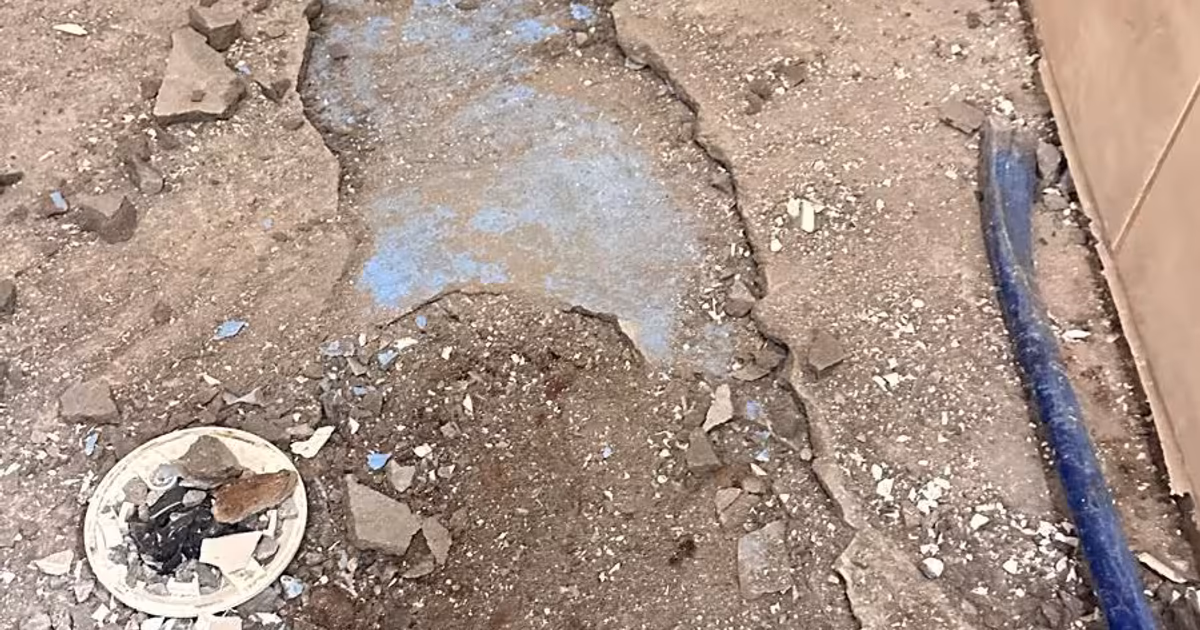 Shower floor in Elizabeth, Colorado during demolition: the broken mortar bed and the failed waterproofing layer exposed around the drain