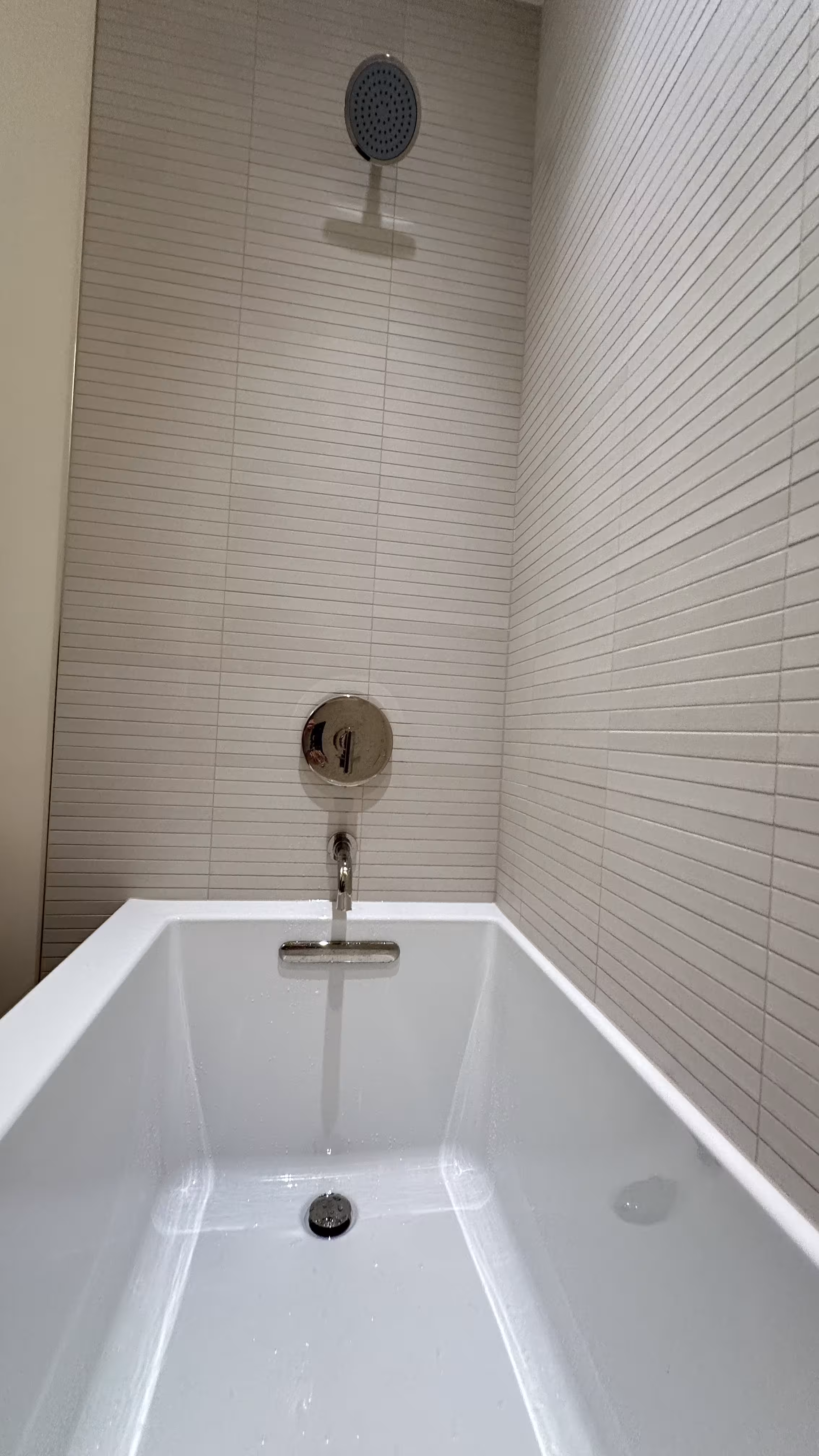Wide view of the alcove tub, shower valve, and kit-kat tile walls in a finished Arvada bathroom