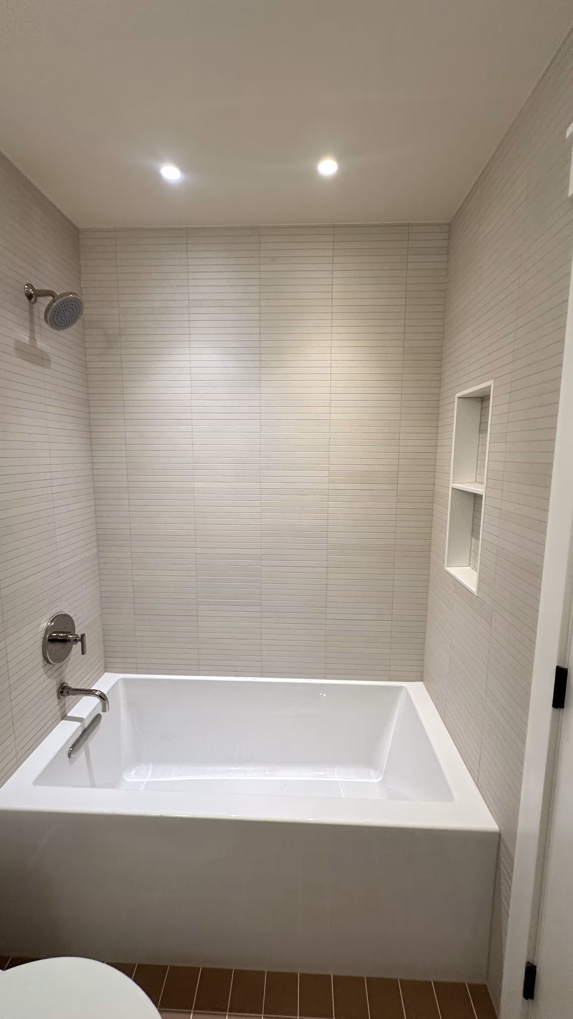 Finished Arvada bathroom with alcove tub, kit-kat tile surround, and two-tier niche shelf
