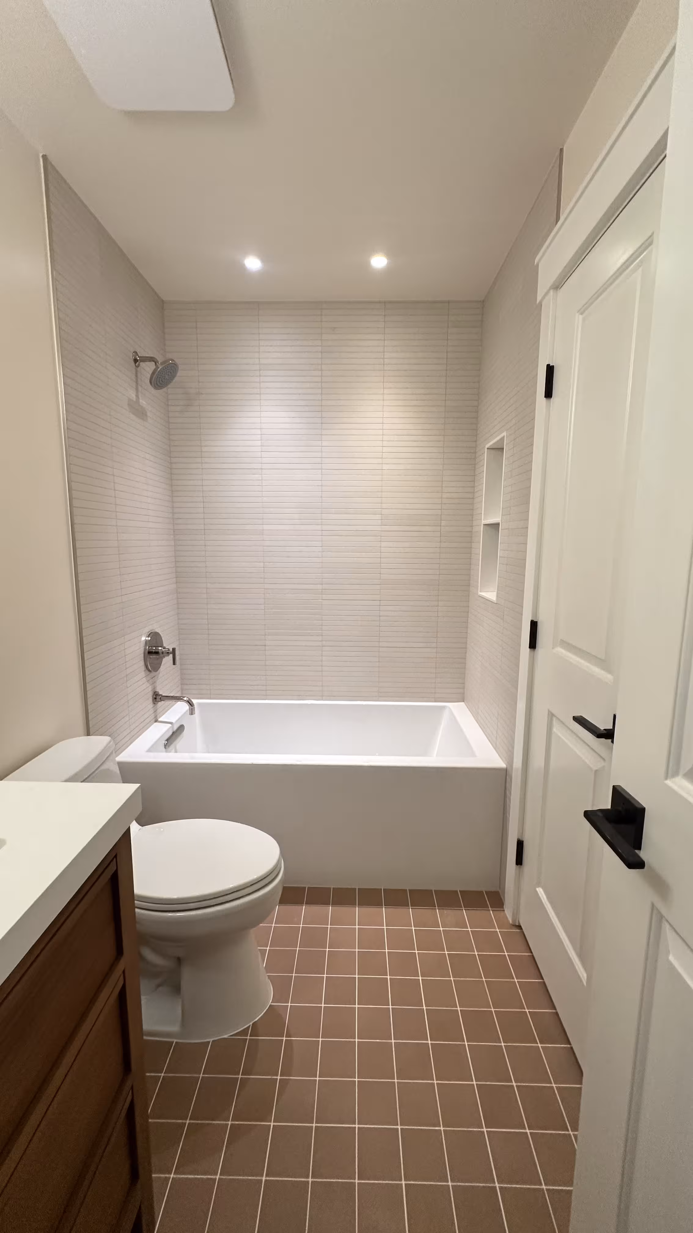 Finished tub bathroom remodel with white kit-kat tile surround and terracotta floor in Arvada CO