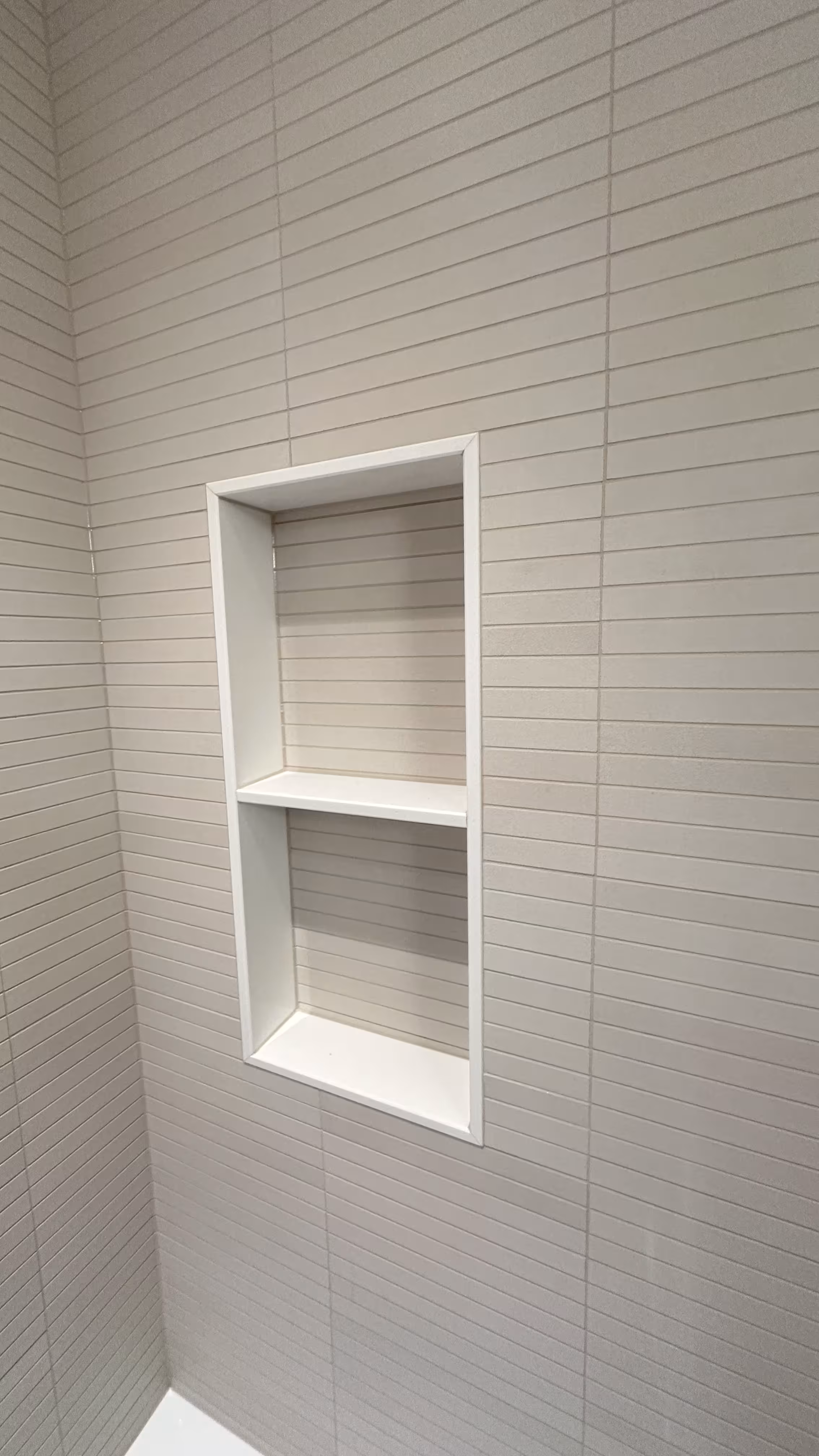 Close-up of the niche shelf dividers finished with white kit-kat tile in an Arvada bathroom remodel
