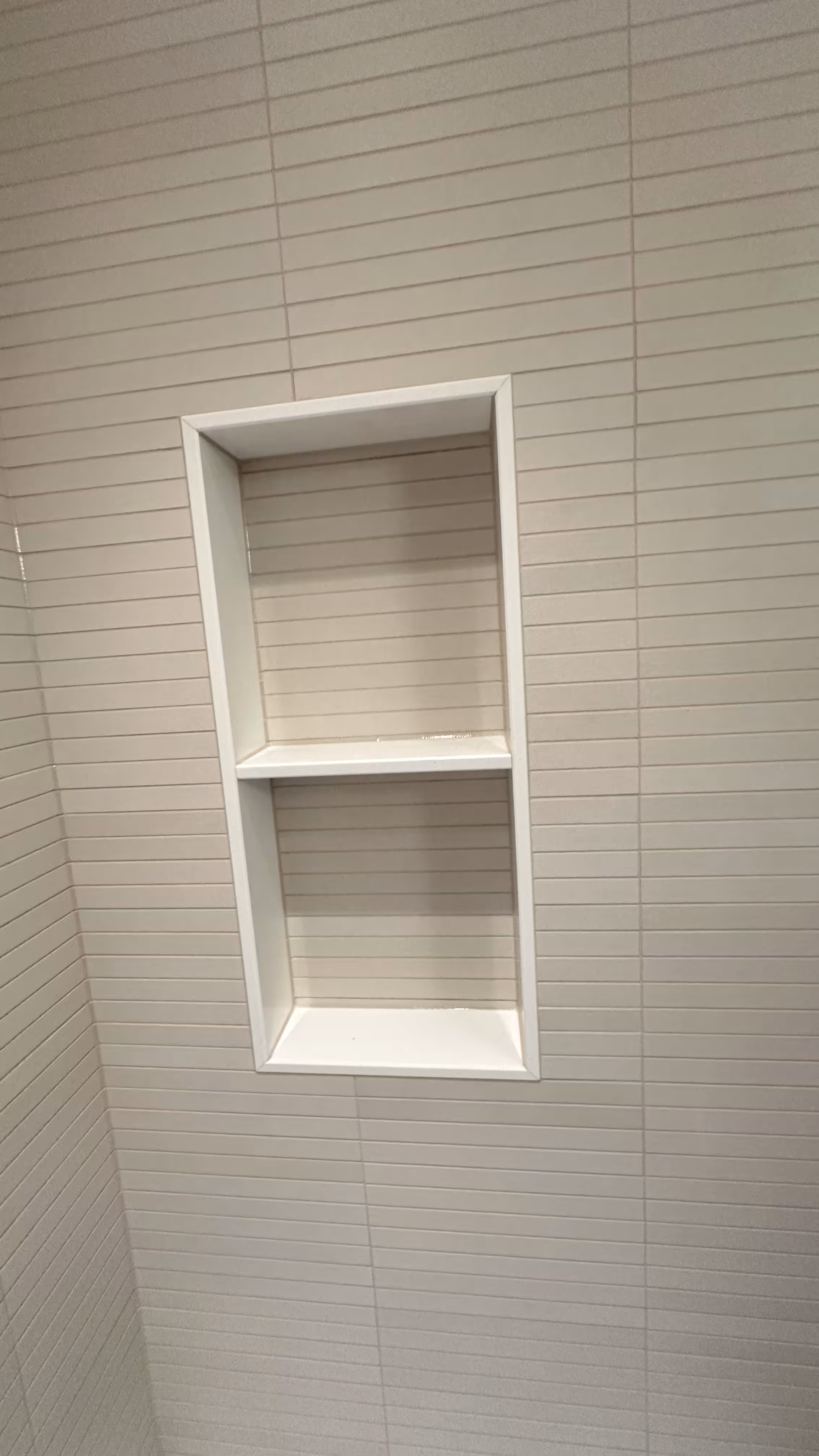 Straight-on view of the finished two-tier tiled niche shelf in an Arvada bathroom remodel