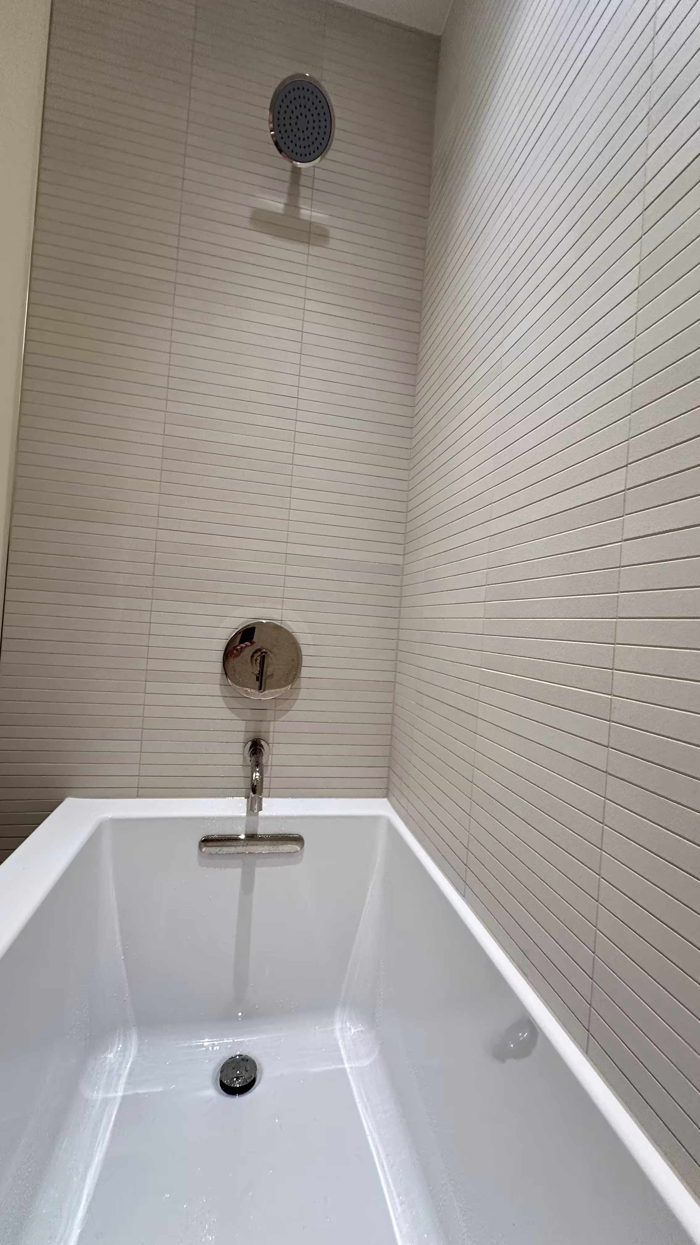 Close-up of the chrome tub filler and water droplets against white kit-kat tile in Arvada