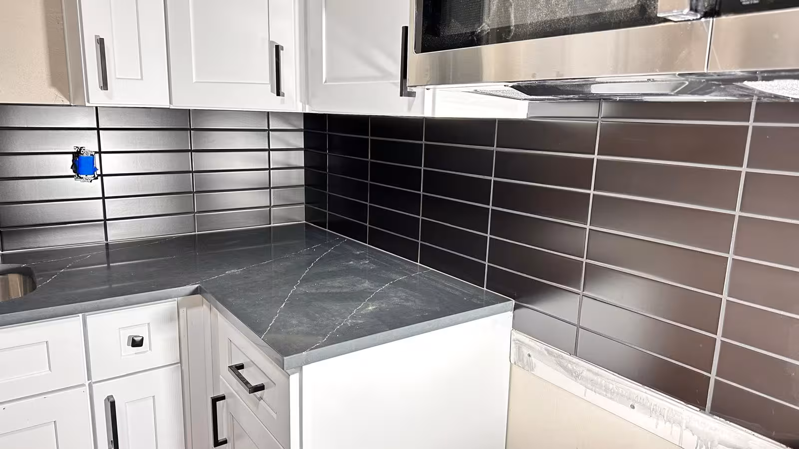 Black subway tile backsplash along kitchen counter run with matching black grout