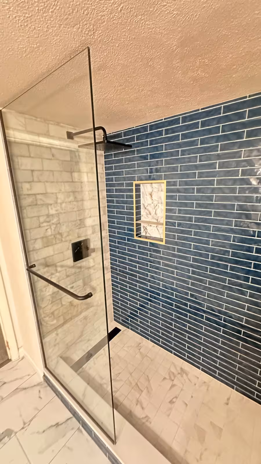 Modern frameless glass shower enclosure in remodeled basement bathroom Aurora Colorado