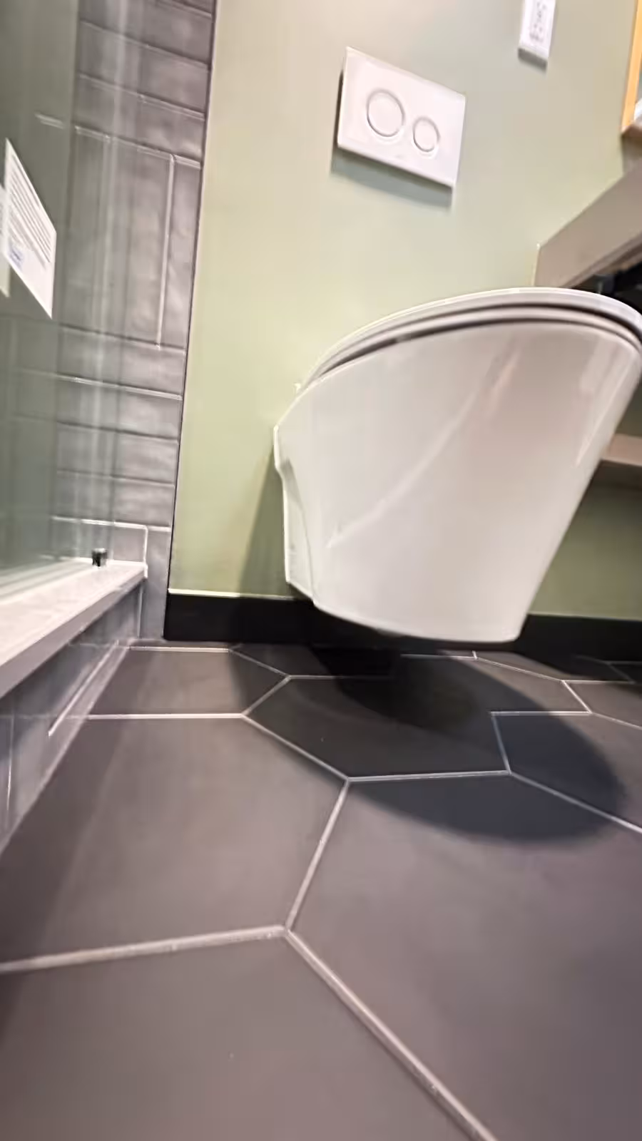 TOTO wall-hung toilet installation detail showing floating design above black hexagon floor tile