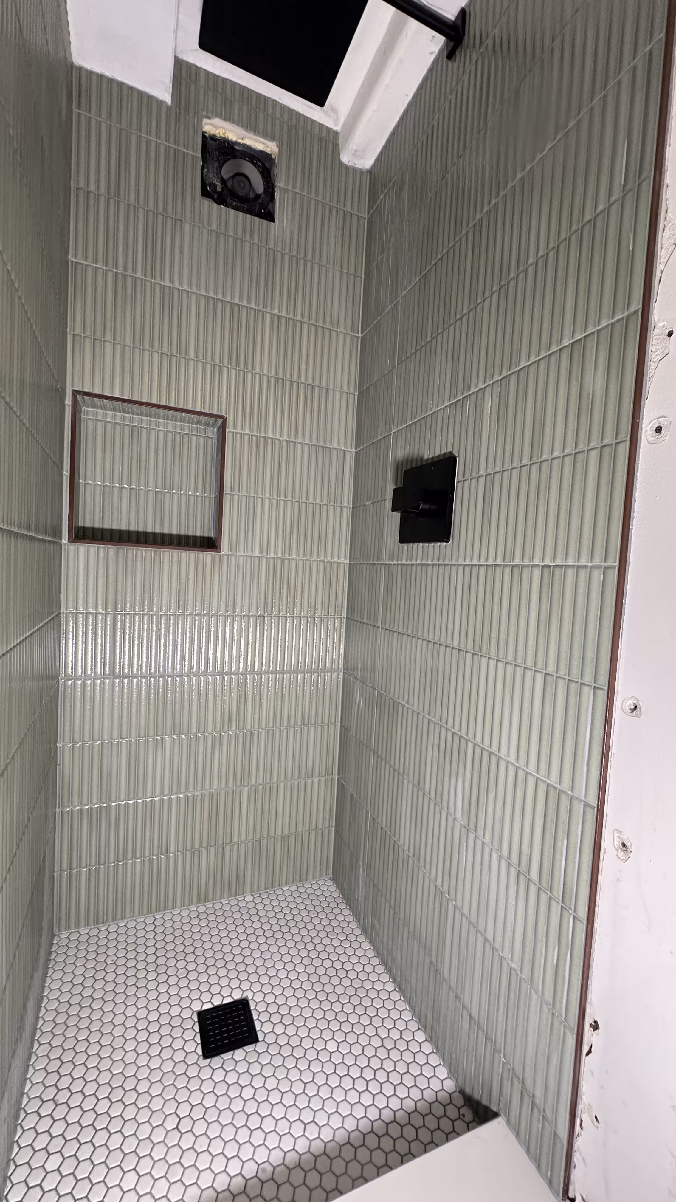 Elevated angle view of the finished green fluted tile shower and white hexagon floor in Arvada, CO