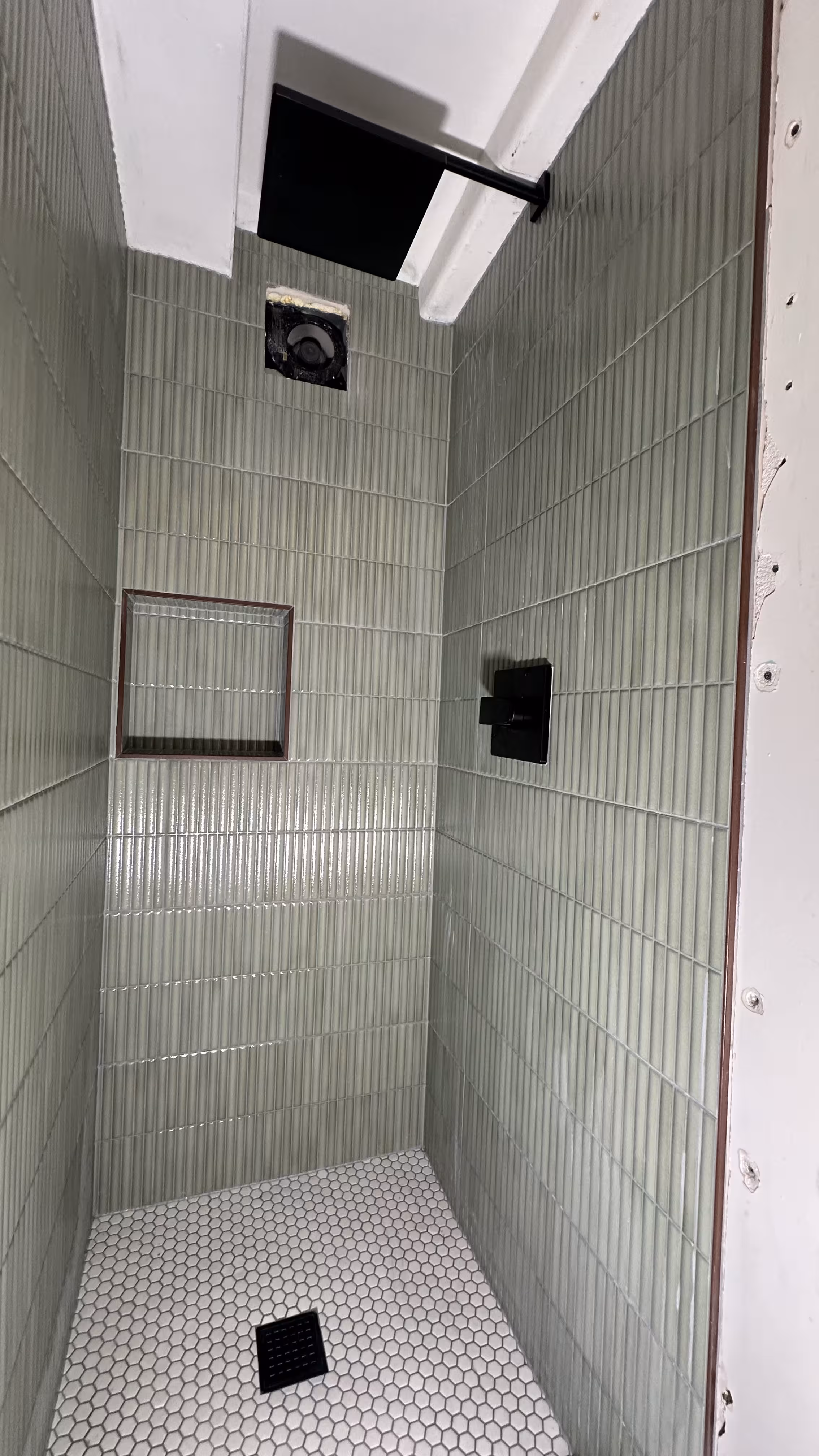 Overview of the completed green fluted tile shower with rain shower head and hexagon floor in Arvada, CO
