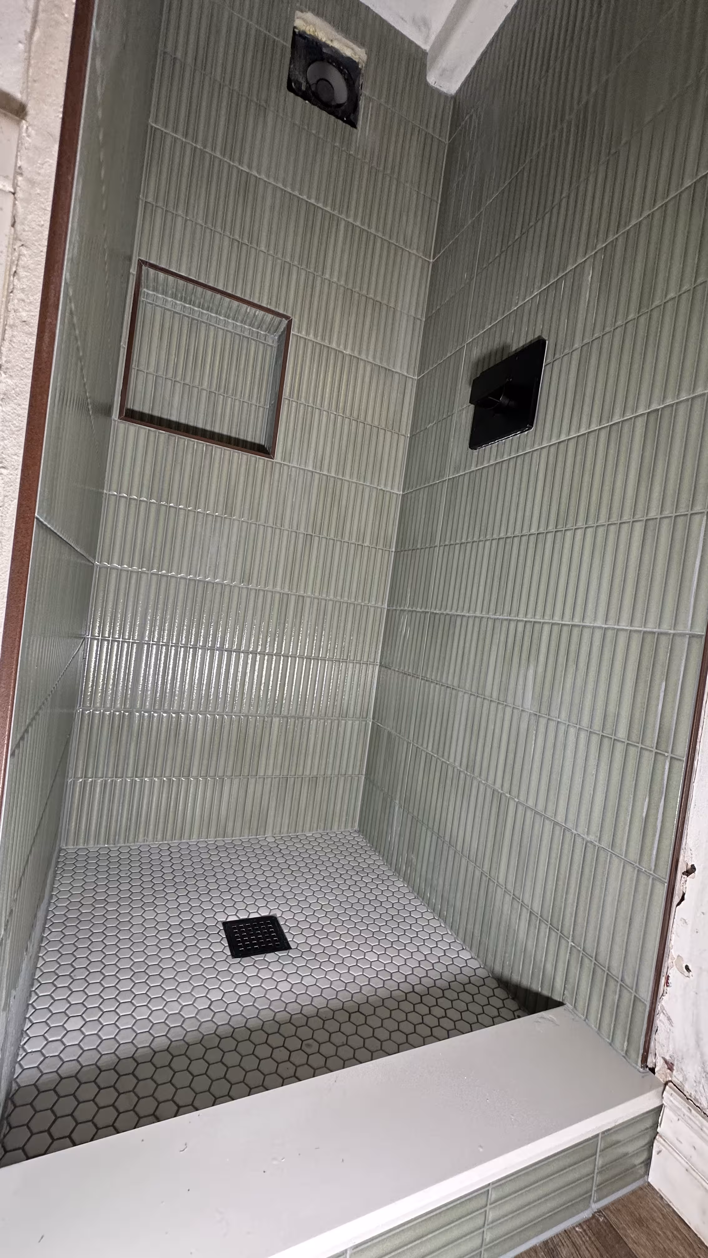 Wide-angle view of the finished green fluted tile shower with black square floor drain in Arvada