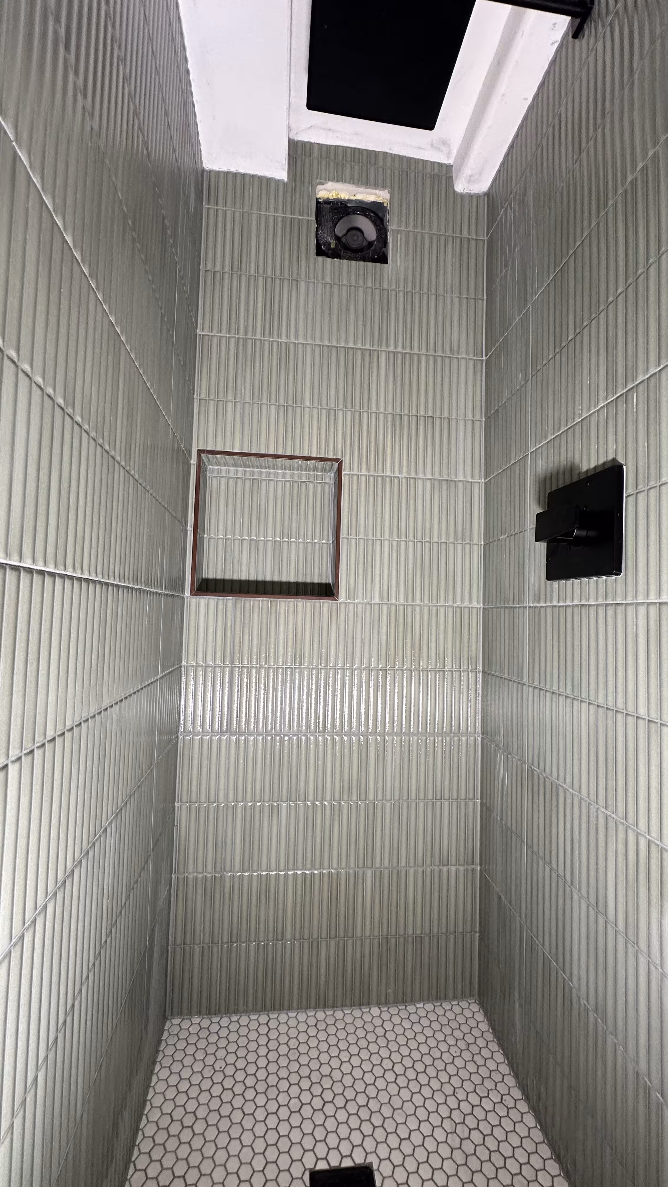 Green fluted tile shower wall detail showing the niche, valve, and ceiling vent opening in Arvada