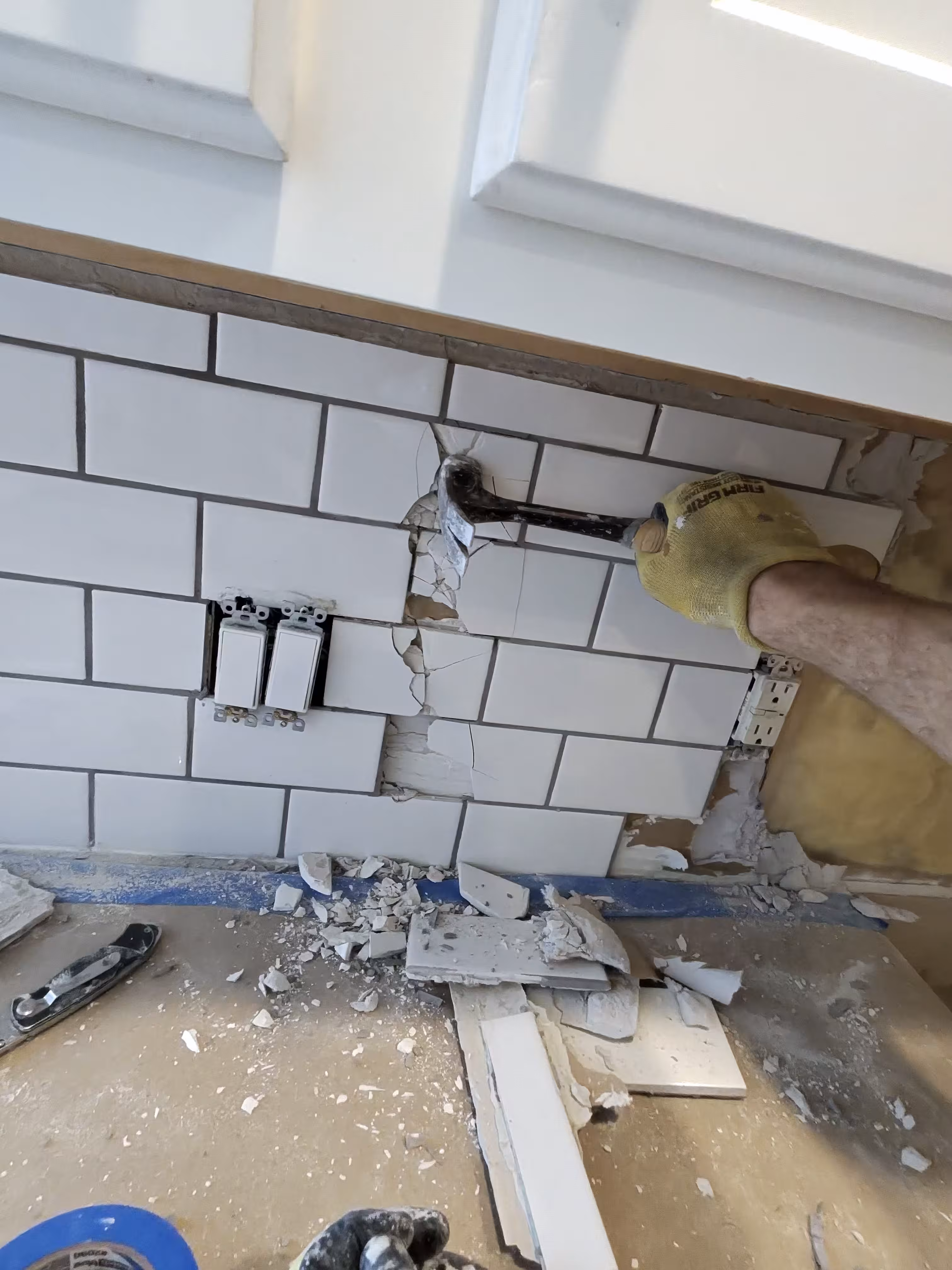 Kitchen backsplash wall stripped down to bare studs and insulation, ready for new tile, in this Aurora renovation