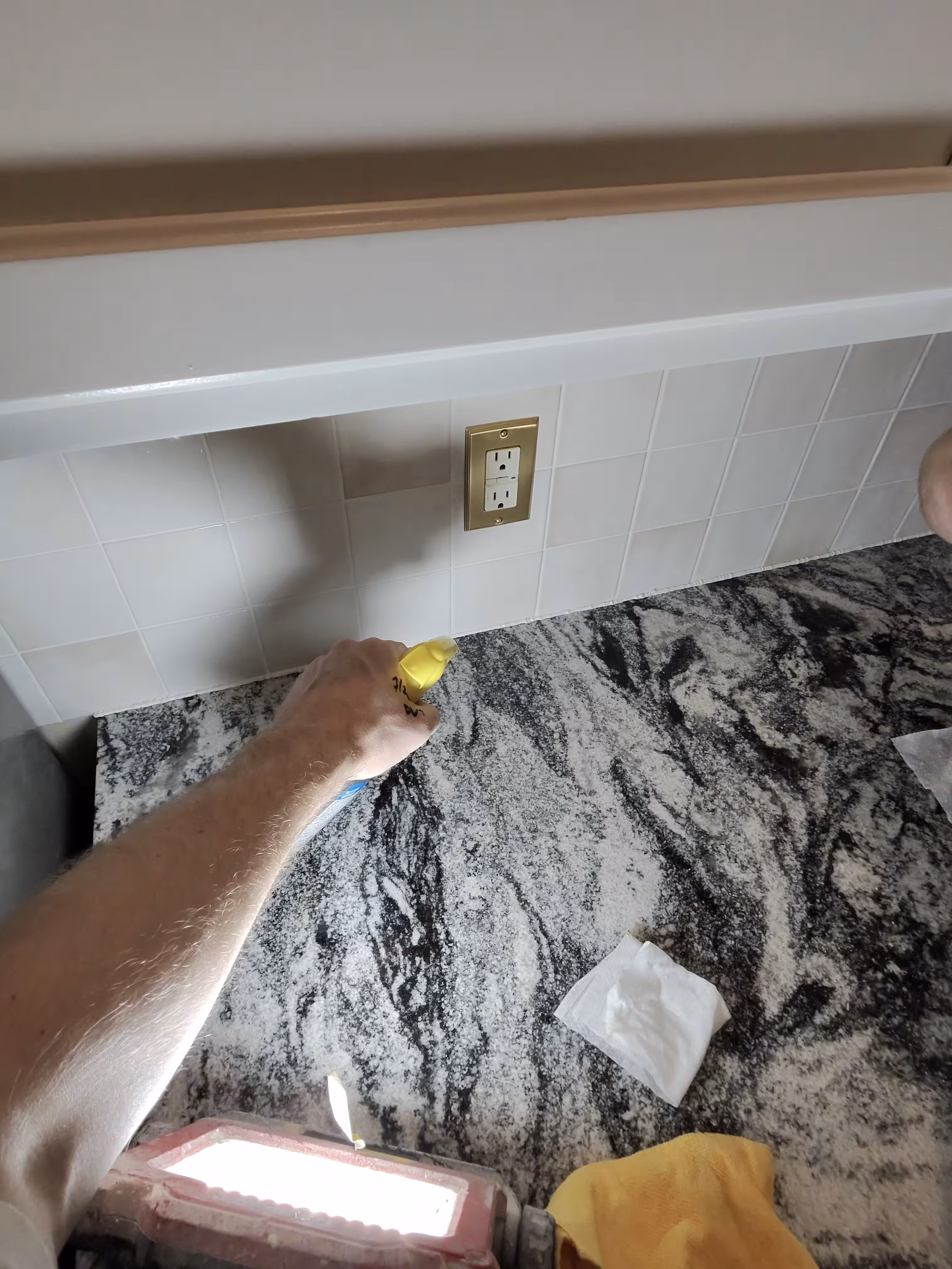 Tooling a smooth silicone caulk line along the countertop edge where it meets the new tile in this Aurora kitchen