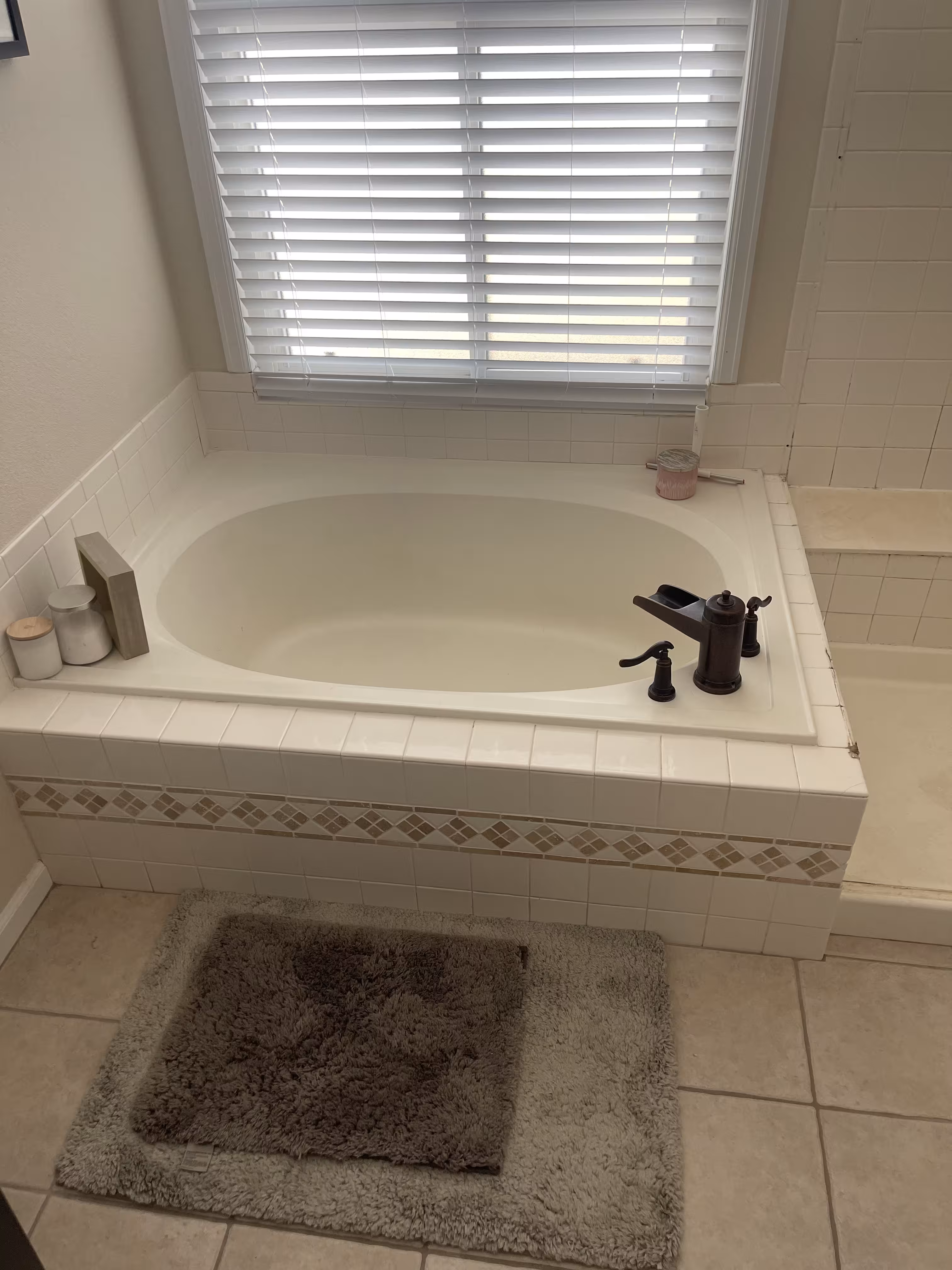 Dated garden tub before remodeling with oil-rubbed bronze faucet and small white tile in this Highlands Ranch master bathroom