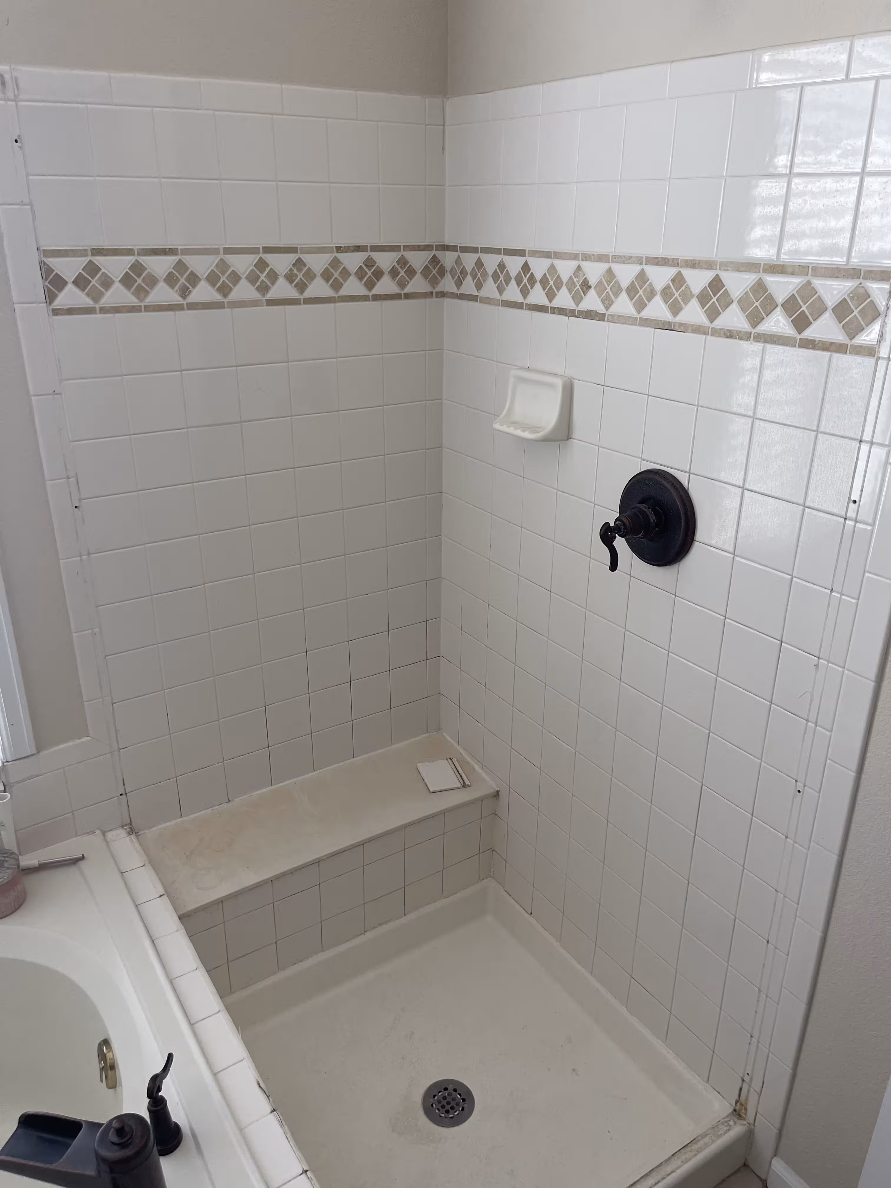 Outdated shower stall before renovation with small white 4x4 tile and a diamond mosaic accent band in Highlands Ranch