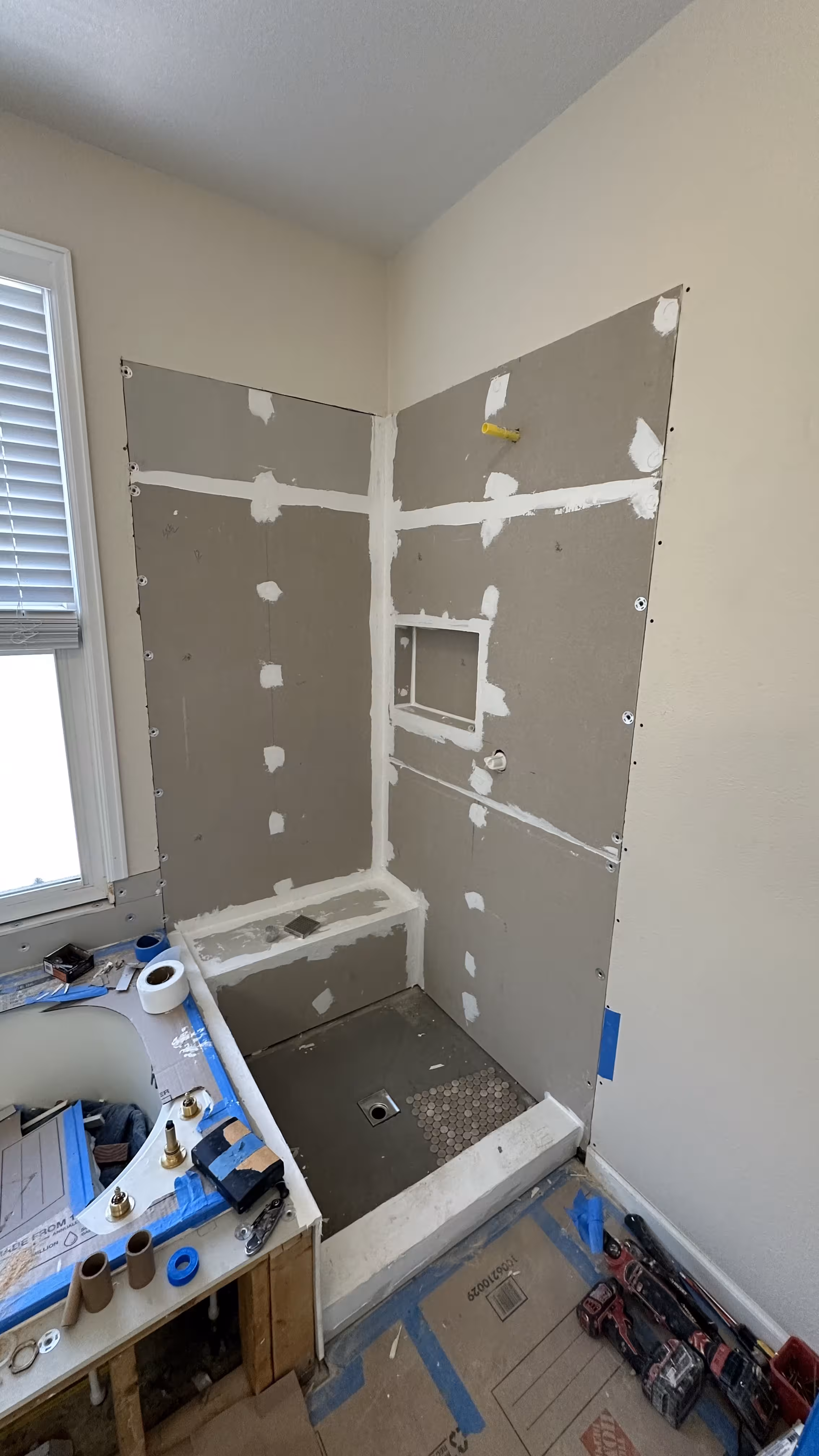Cement backer board shower walls with a framed-out storage niche and bench base ready for tile in this Highlands Ranch master bathroom