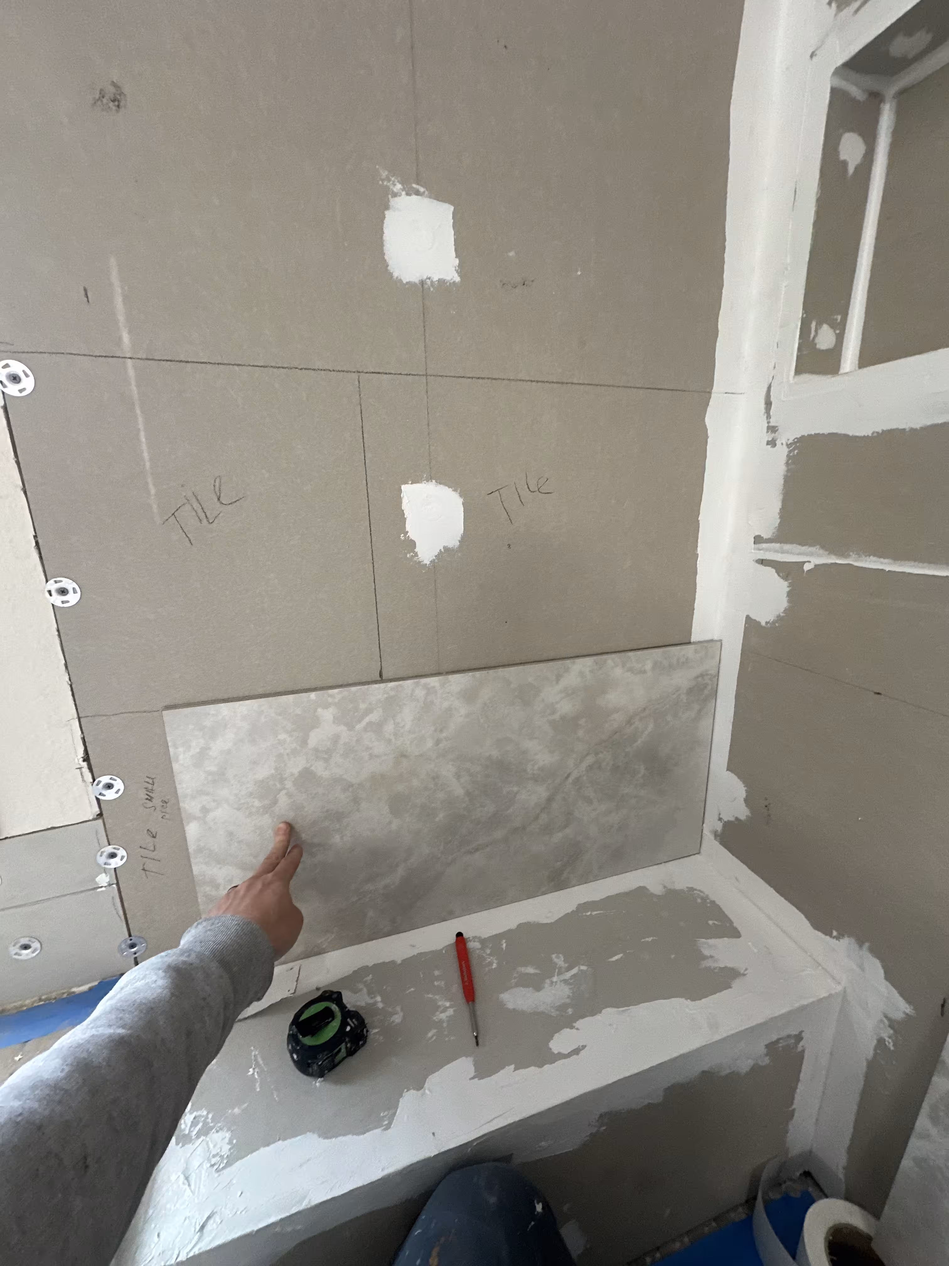 Pencil layout marks and chalk lines on the backer board guide wall tile placement in this Highlands Ranch shower remodel