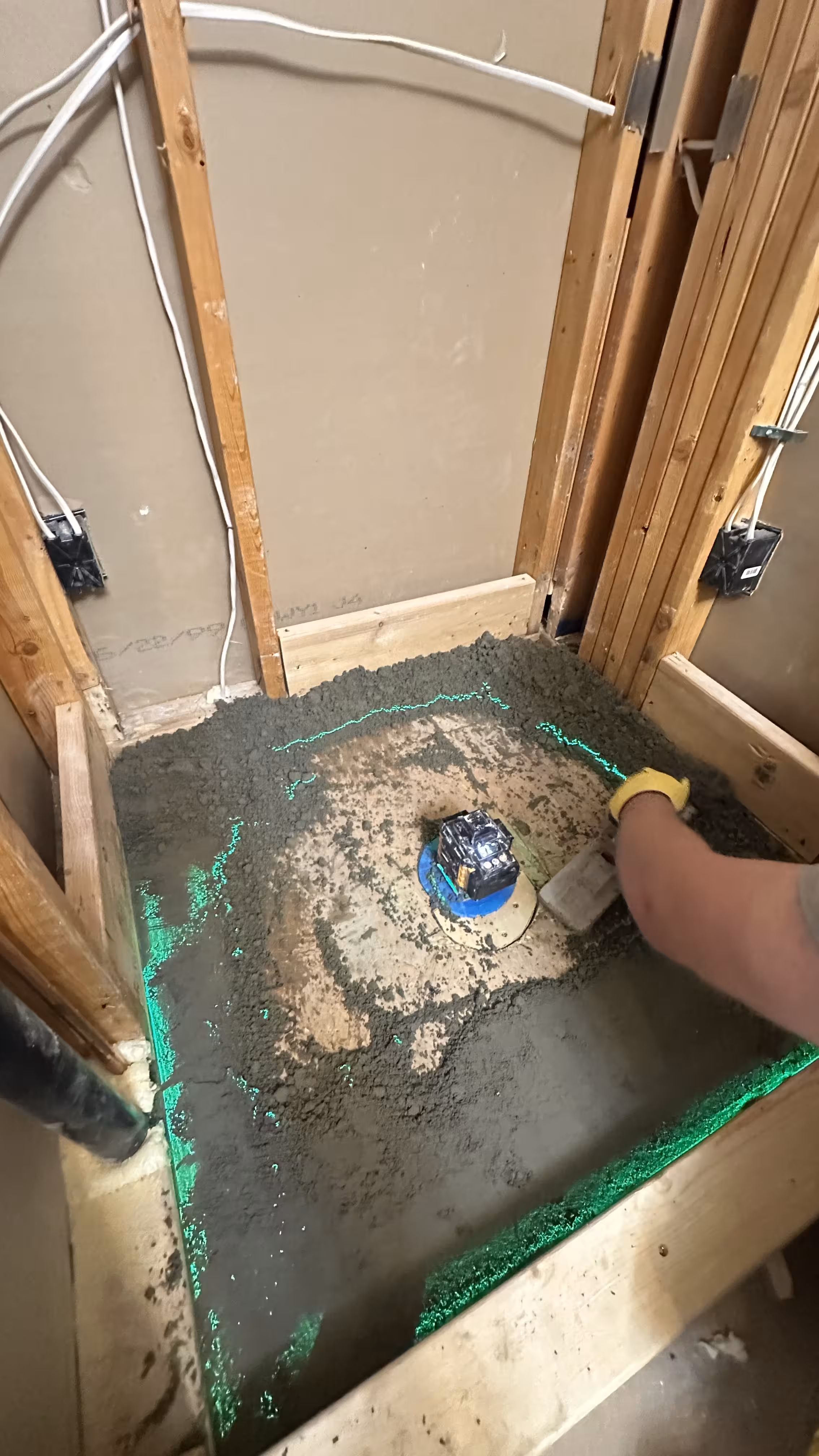 New shower drain set in a freshly floated mortar pre-slope mud bed with exposed wall framing during this Highlands Ranch master bath remodel