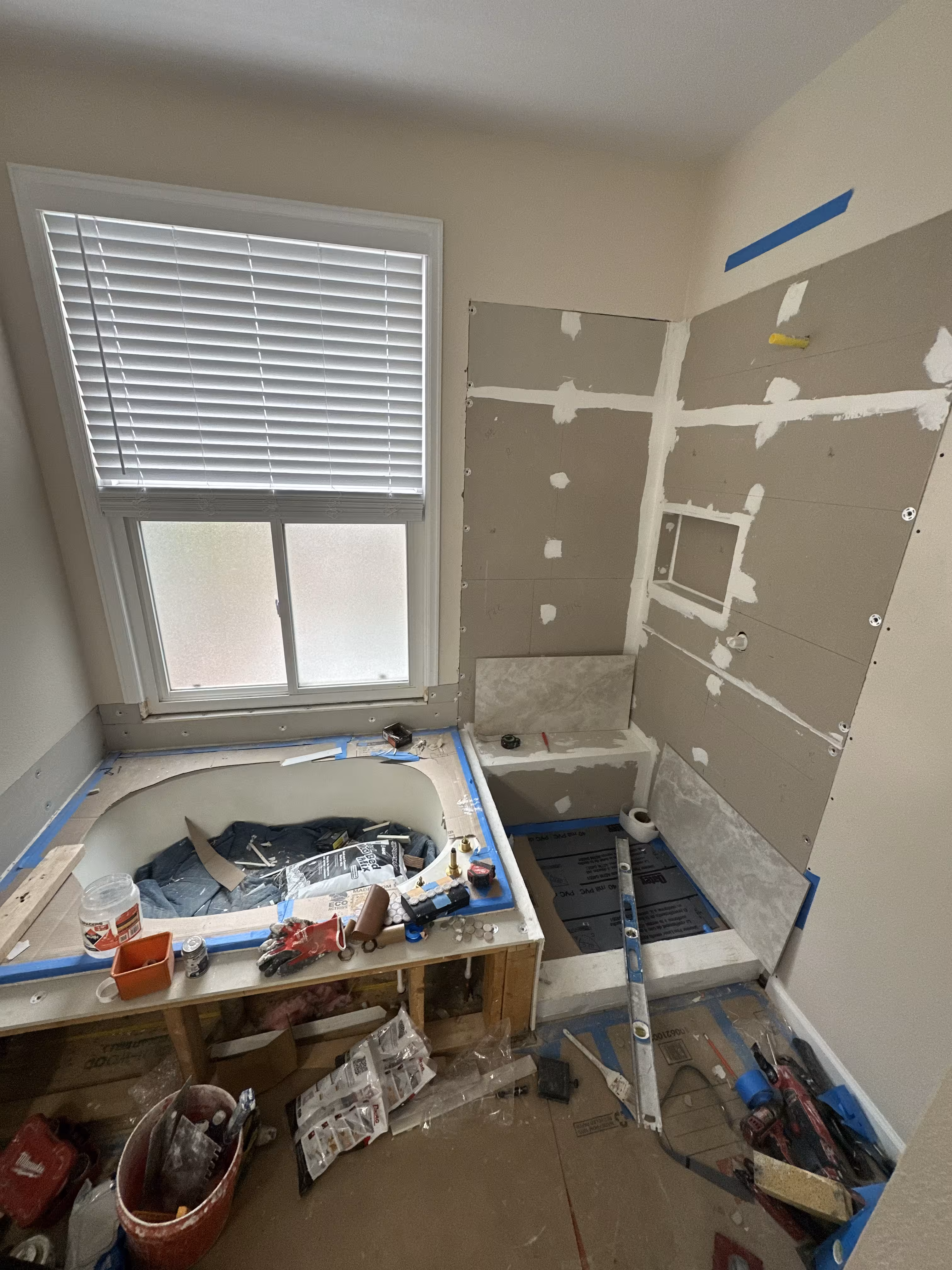 Protected soaking tub installed below the window while cement board shower walls with a framed-out niche await tile, Highlands Ranch