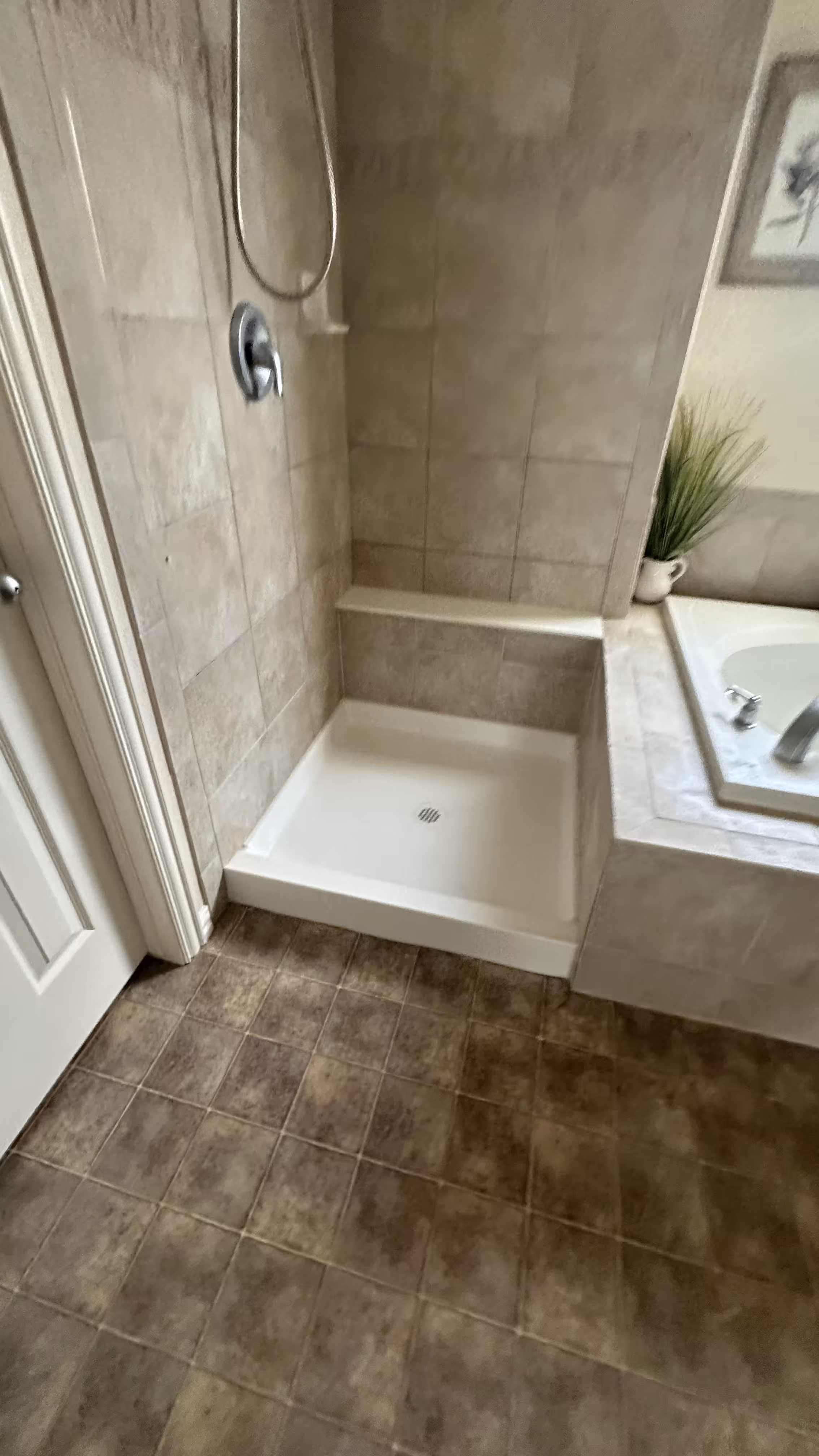 Tiled bench seat inside the rebuilt shower stepping down to the tub deck in Aurora