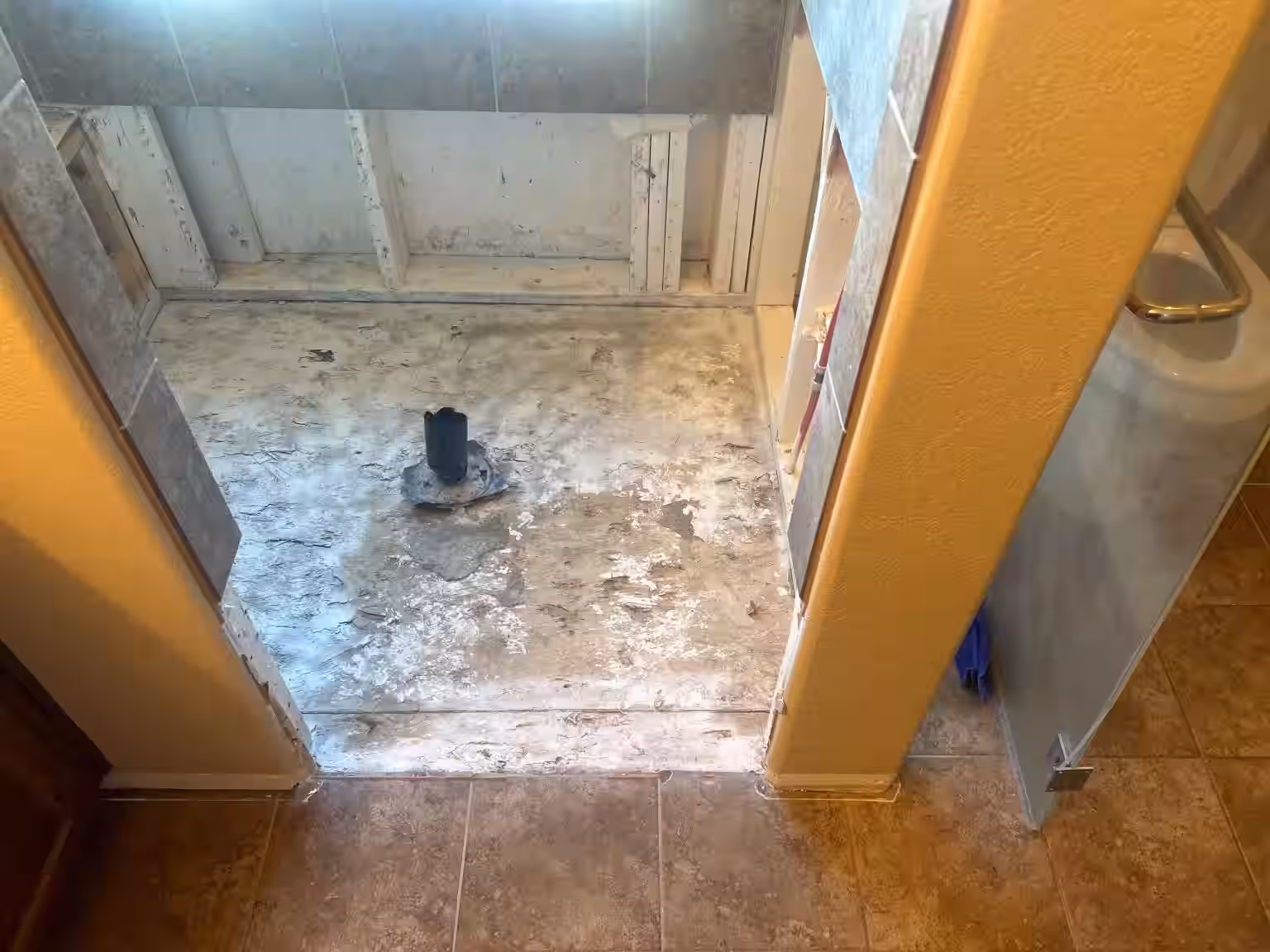 Water-damaged shower floor with failed shower pan requiring emergency repair