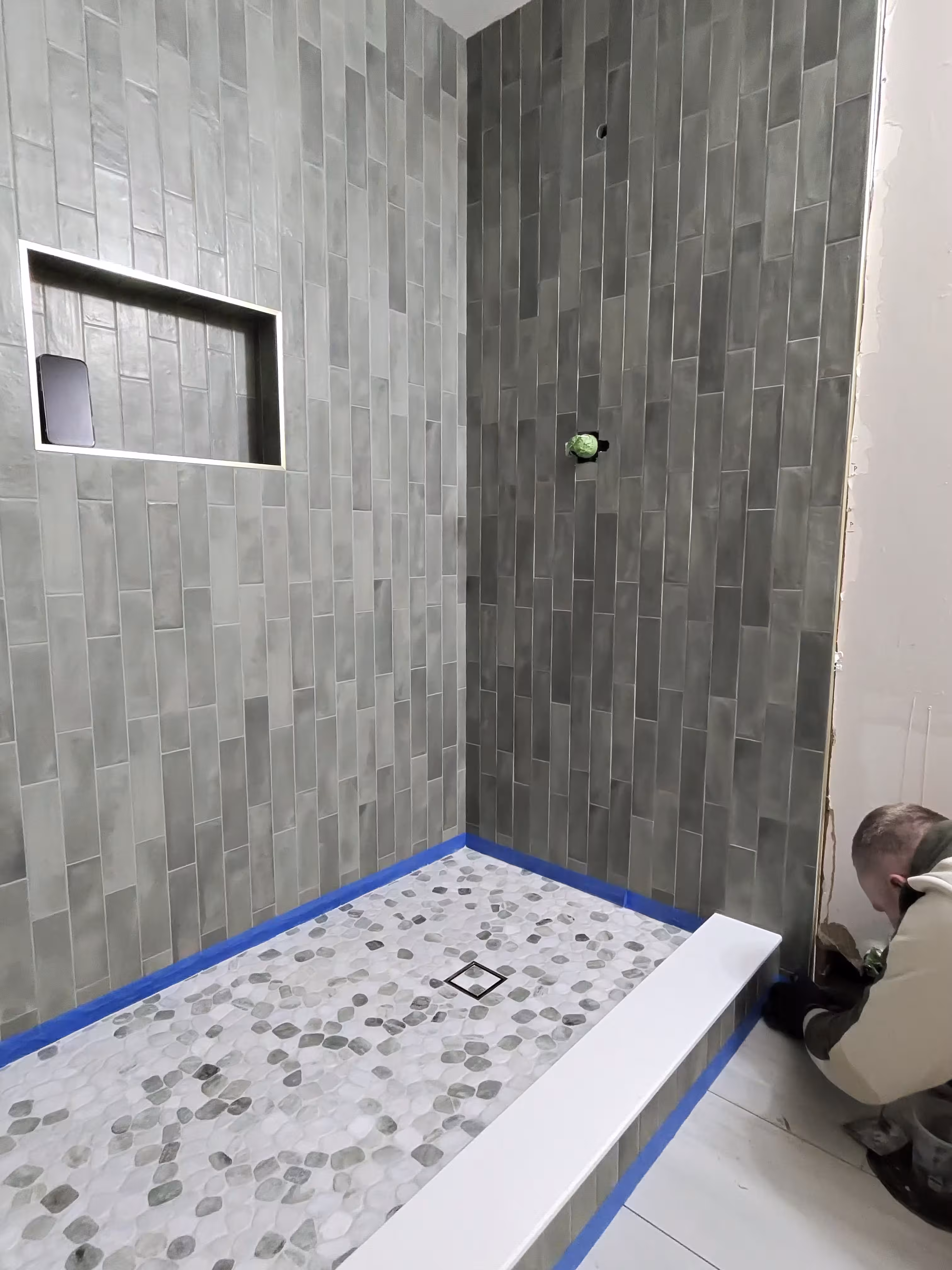 Green stacked tile shower with a pebble stone floor freshly installed in Commerce City, CO
