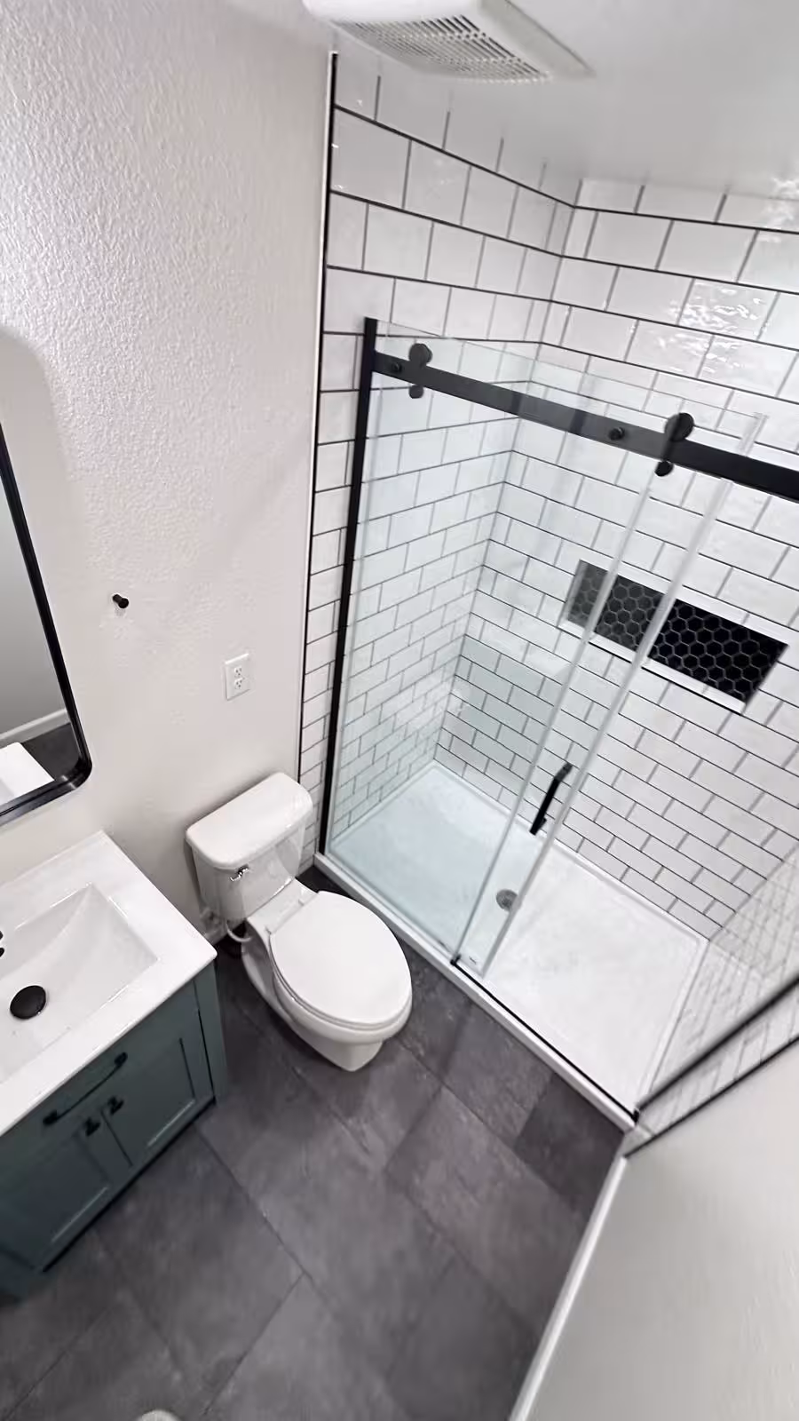 Small bathroom remodel with white subway tile shower and black-framed glass door