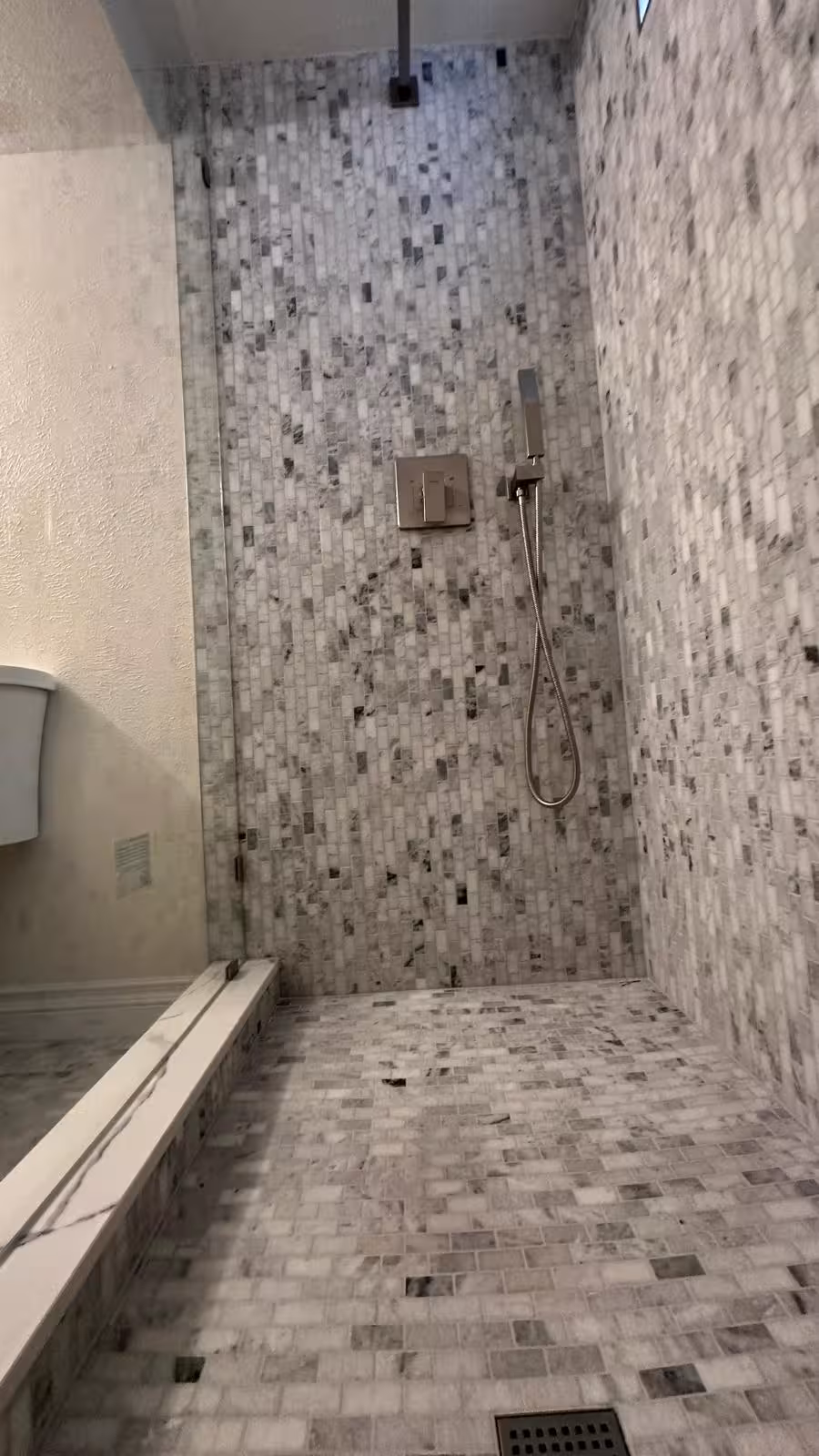 Basement shower with marble bench and handheld spray fixture Littleton