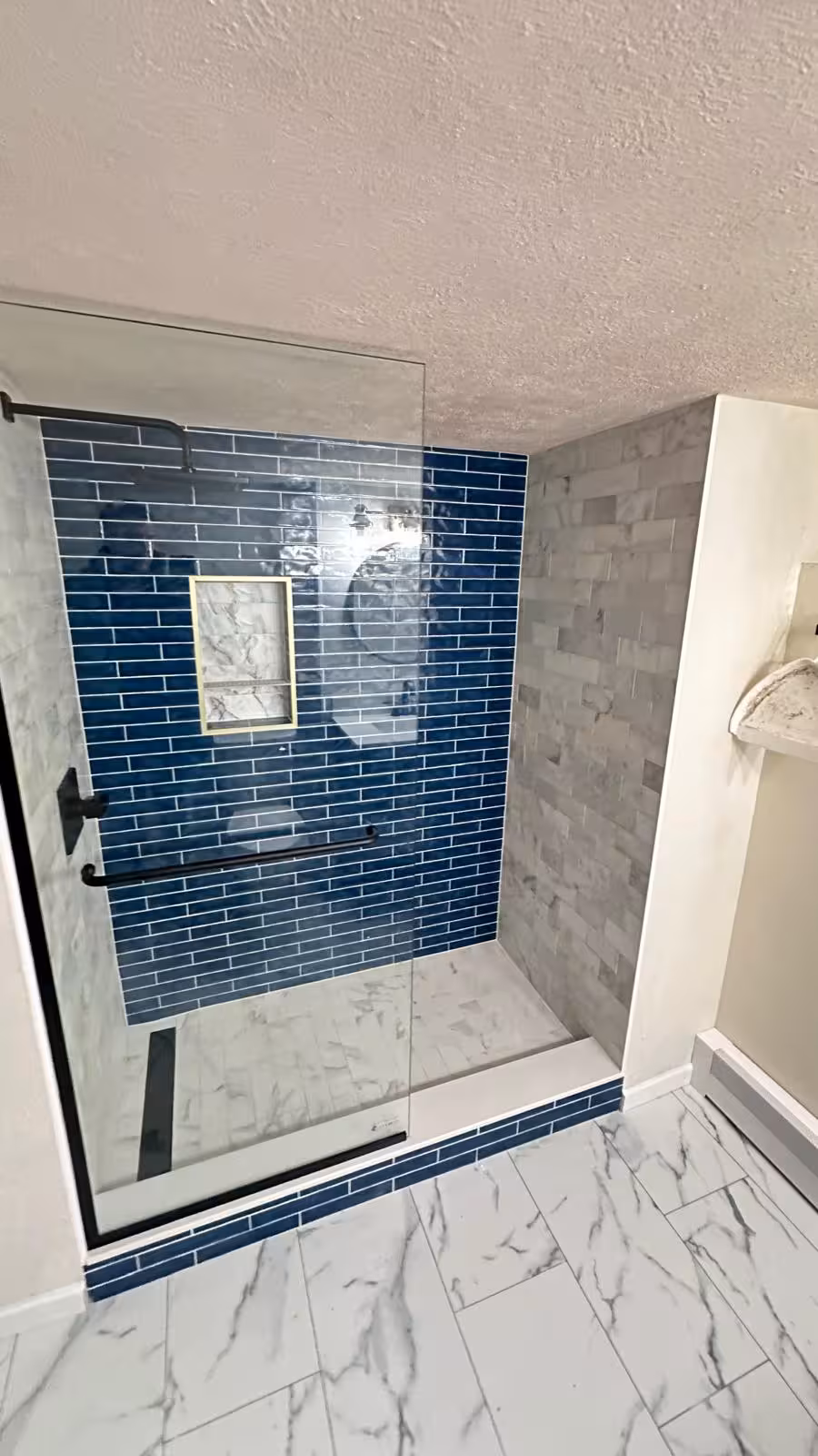 Finished basement shower featuring blue subway accent tile and marble side walls in Aurora home