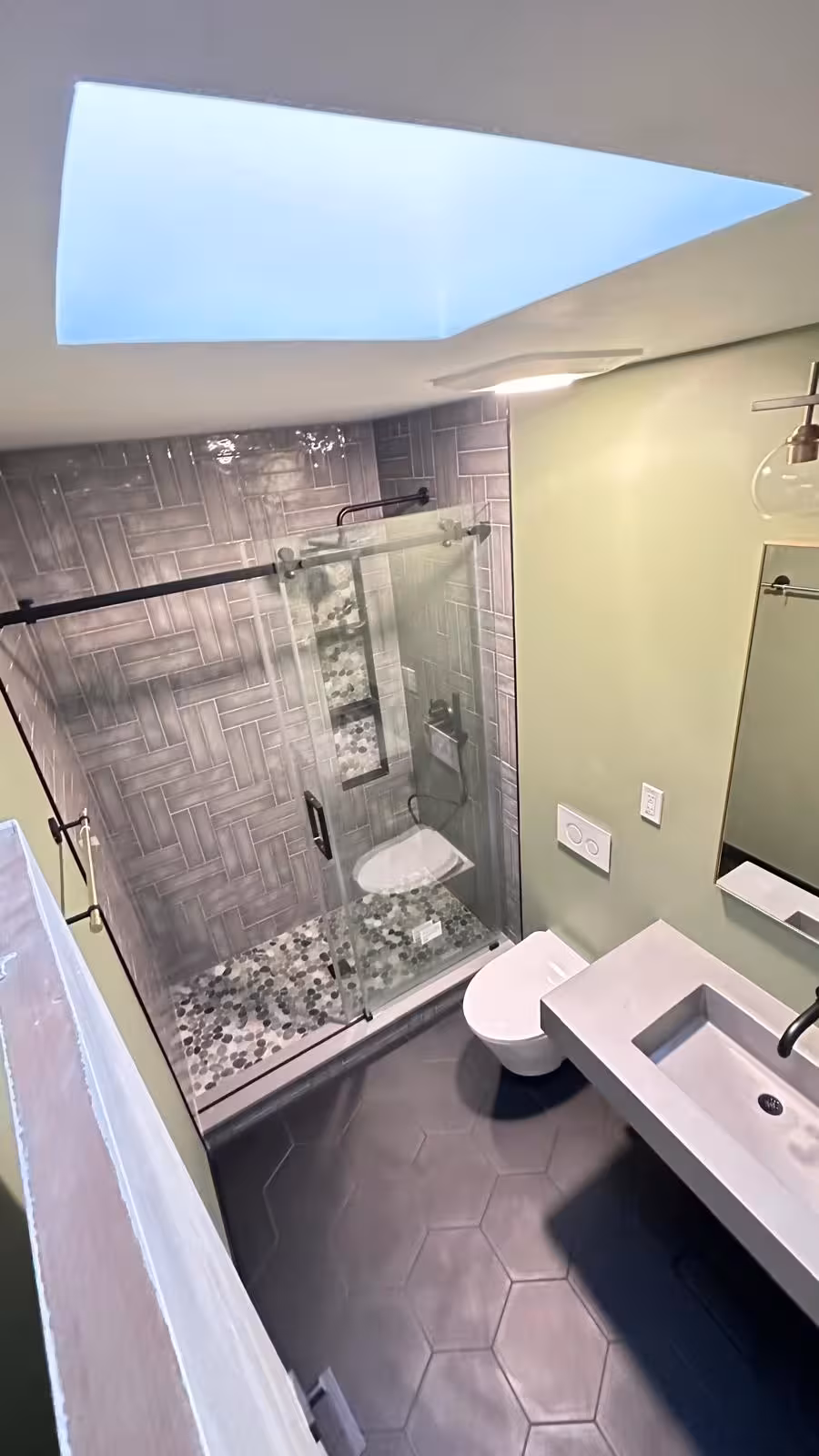 Finished Littleton bathroom renovation showing wall-hung toilet pebble shower floor black hexagon tile