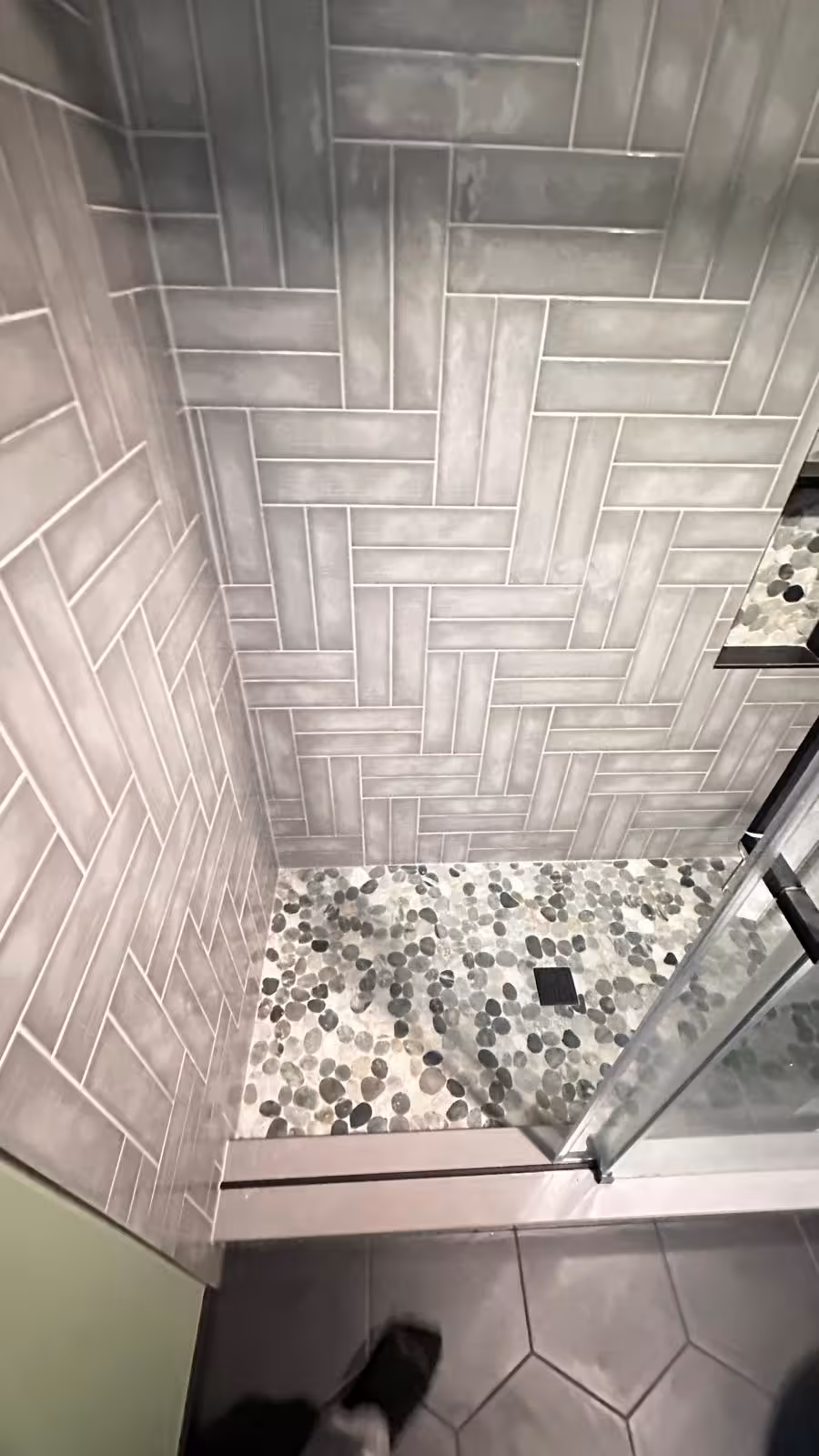 Custom shower floor with river pebble stone mosaic and modern black drain fixture