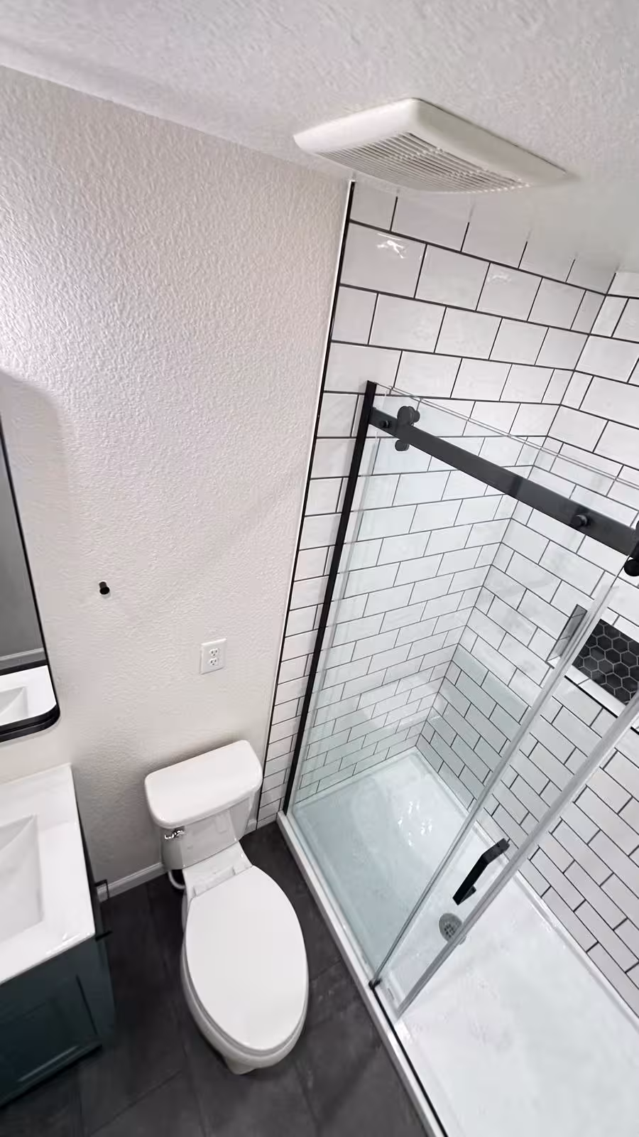 Compact bathroom renovation featuring walk-in shower and glass enclosure