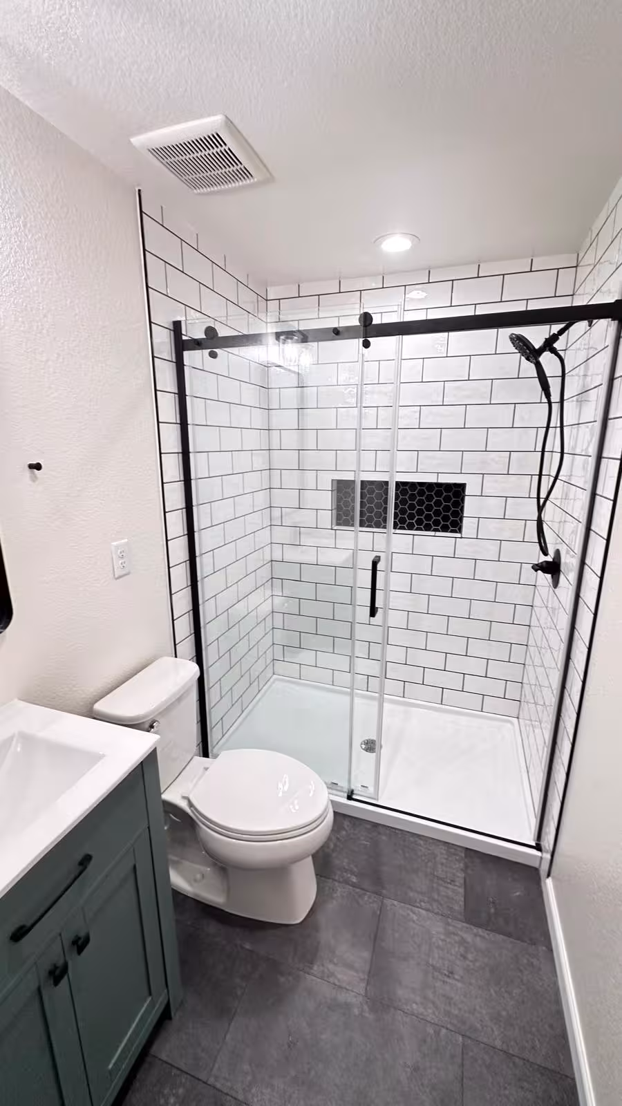 Small bathroom tile remodel with glass shower door front view