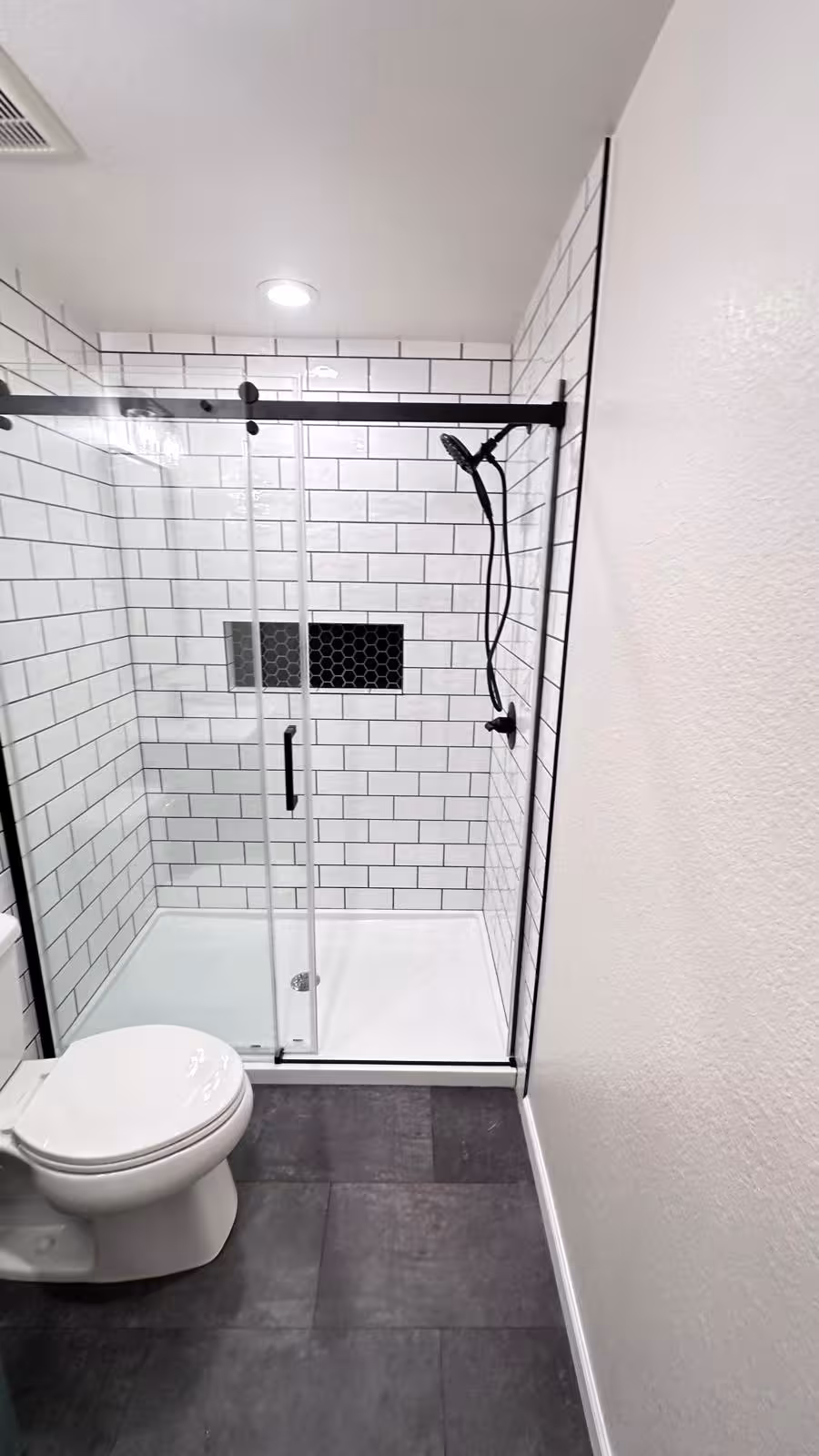Small bathroom renovation with vanity and tiled shower overhead perspective