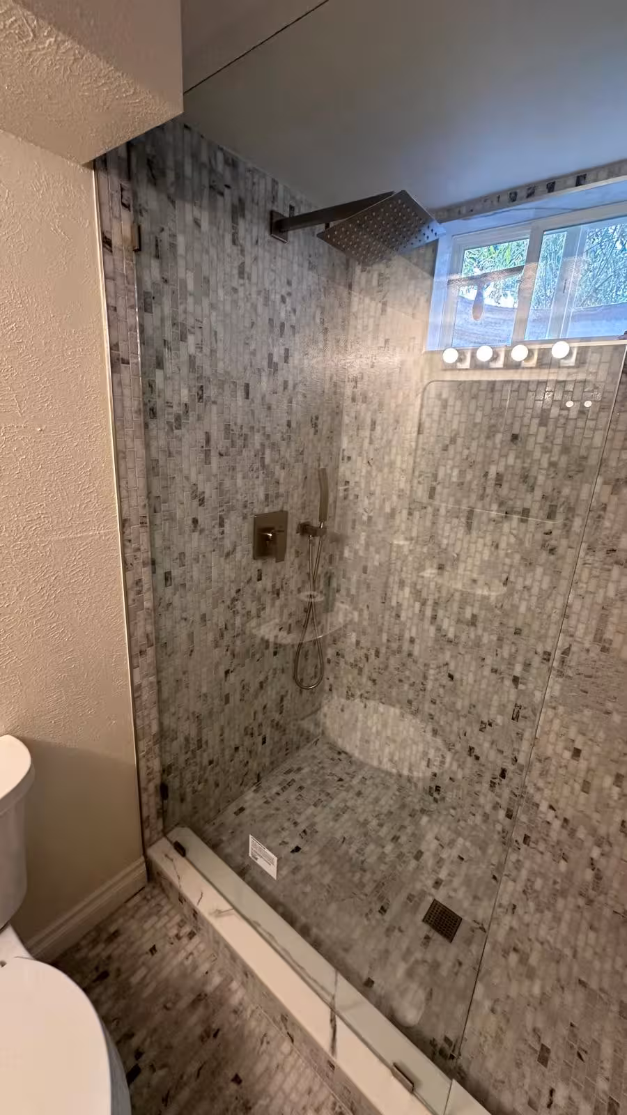 Frameless shower enclosure with marble mosaic walls Littleton basement bathroom